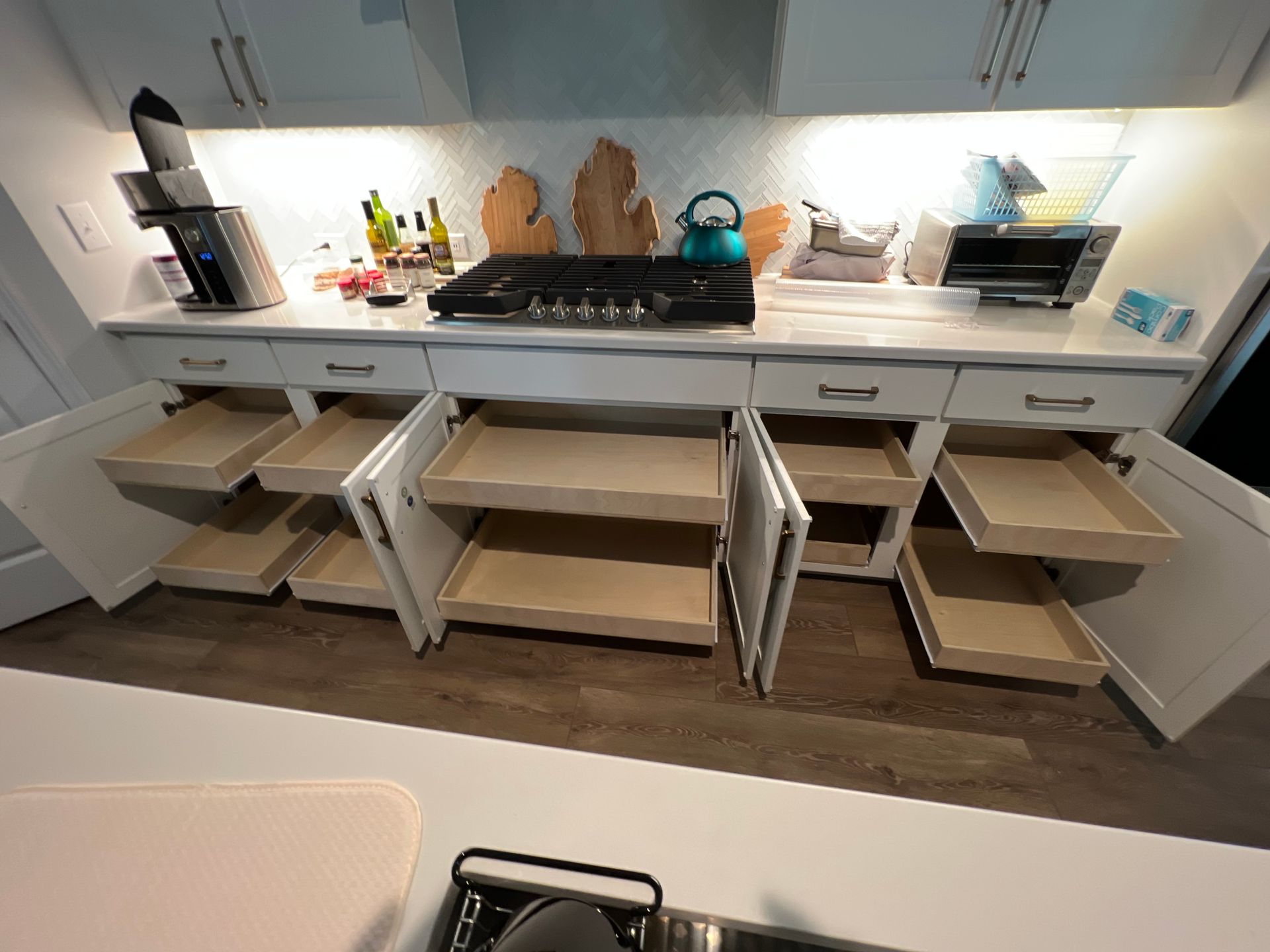 Modern kitchen with open pull-out drawers and pantry shelves beneath a countertop.