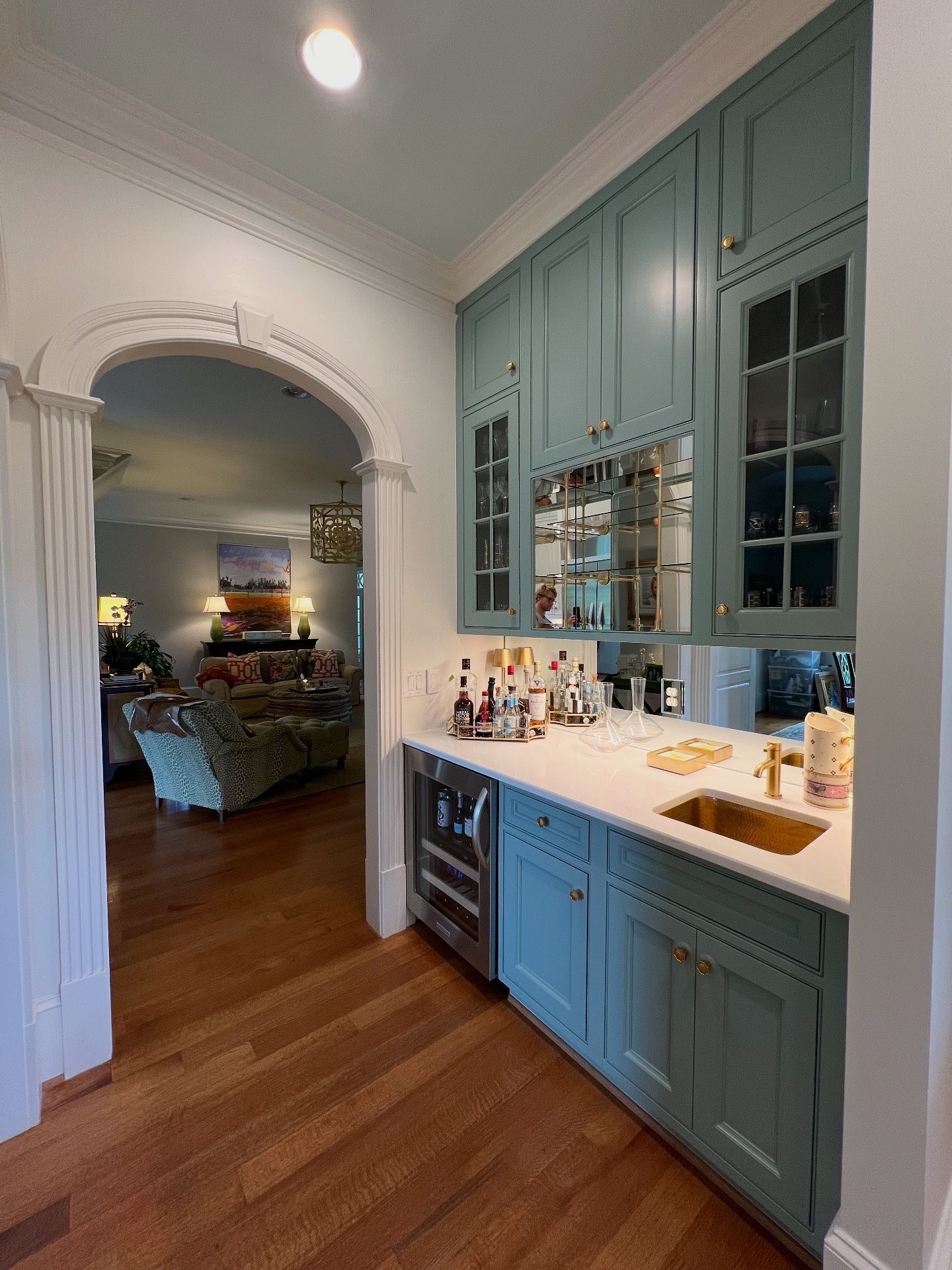 Blue built-in cabinets and white countertop in a hallway, with an arched doorway into a bedroom.