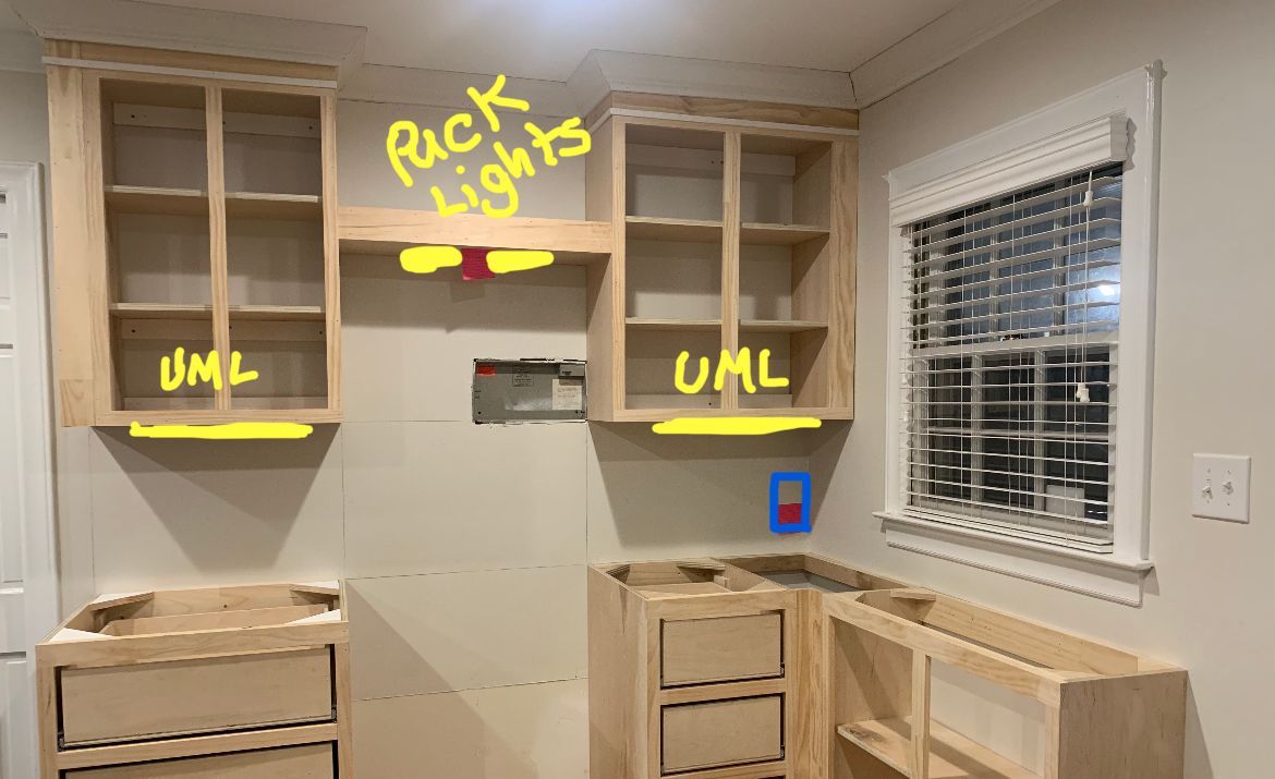 Unfinished kitchen cabinets with yellow annotations marking UMs and “back lights” above the sink area