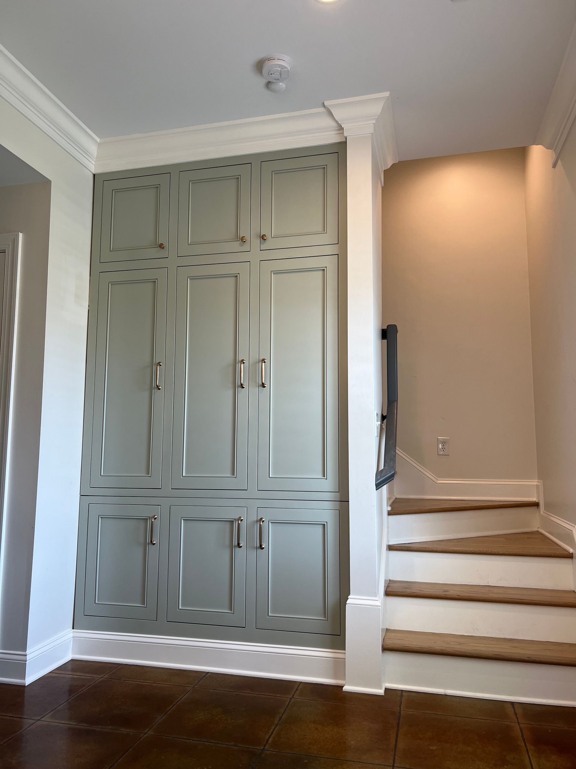 Built-in gray cabinets beside a staircase in a home interior
