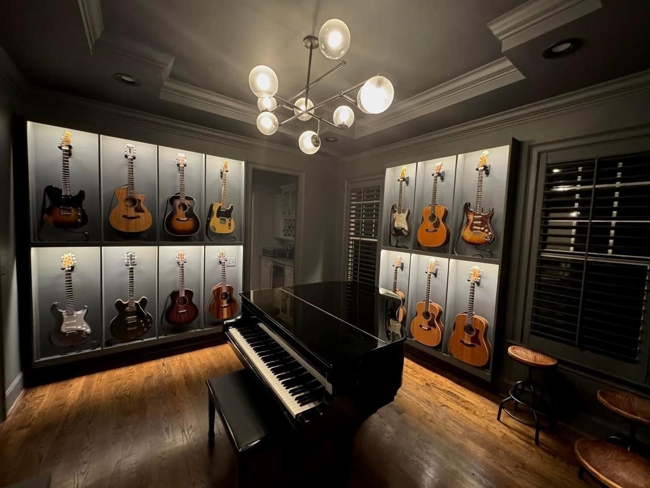 Grand piano in a guitar showroom with wall-mounted guitars and warm chandelier lighting