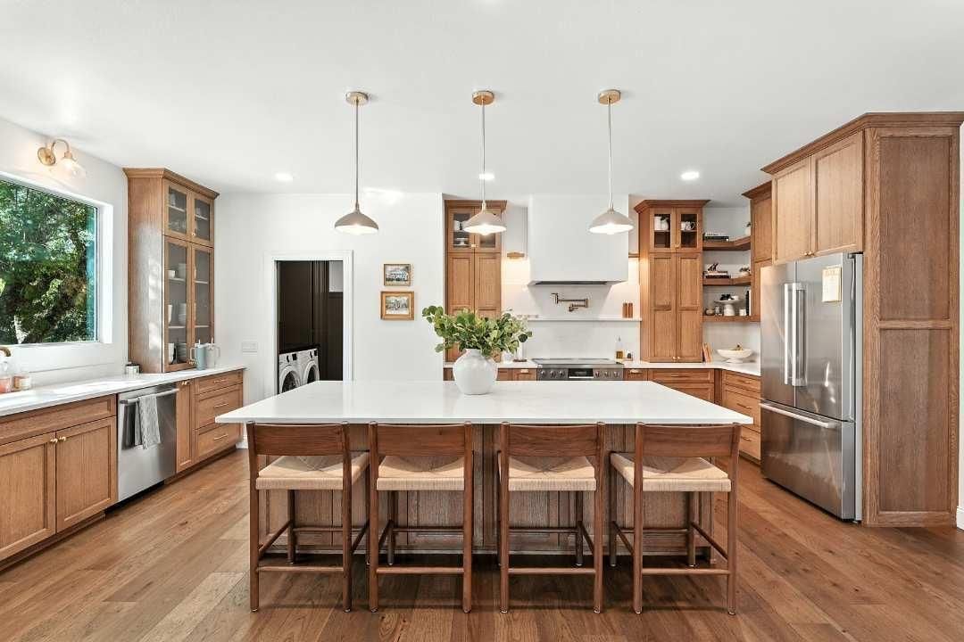 Bright modern kitchen with a large island, wood cabinets, stainless steel appliances, and pendant lights.