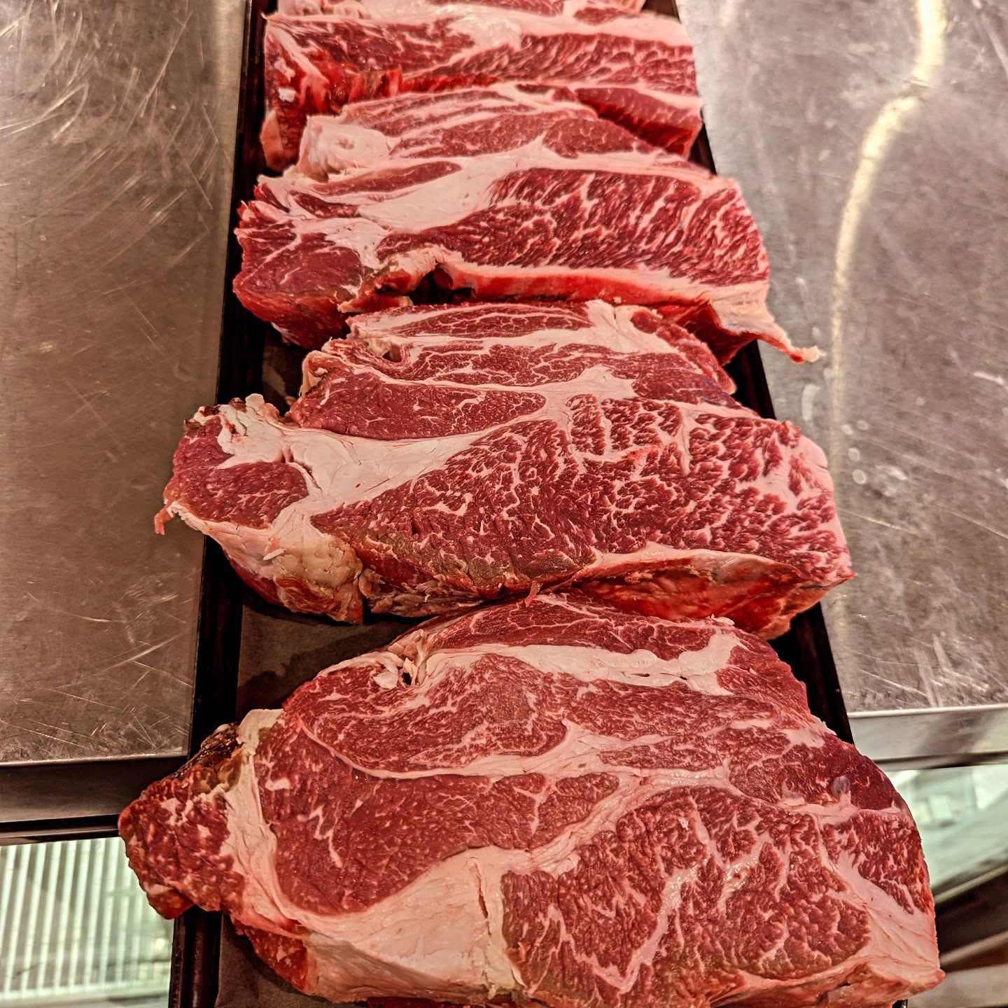 A tray of raw steaks is sitting on a counter.