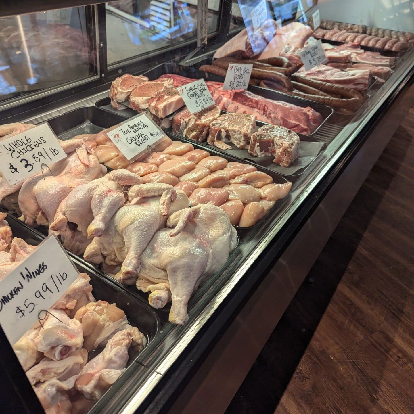 A butcher 's display case filled with chicken and meat