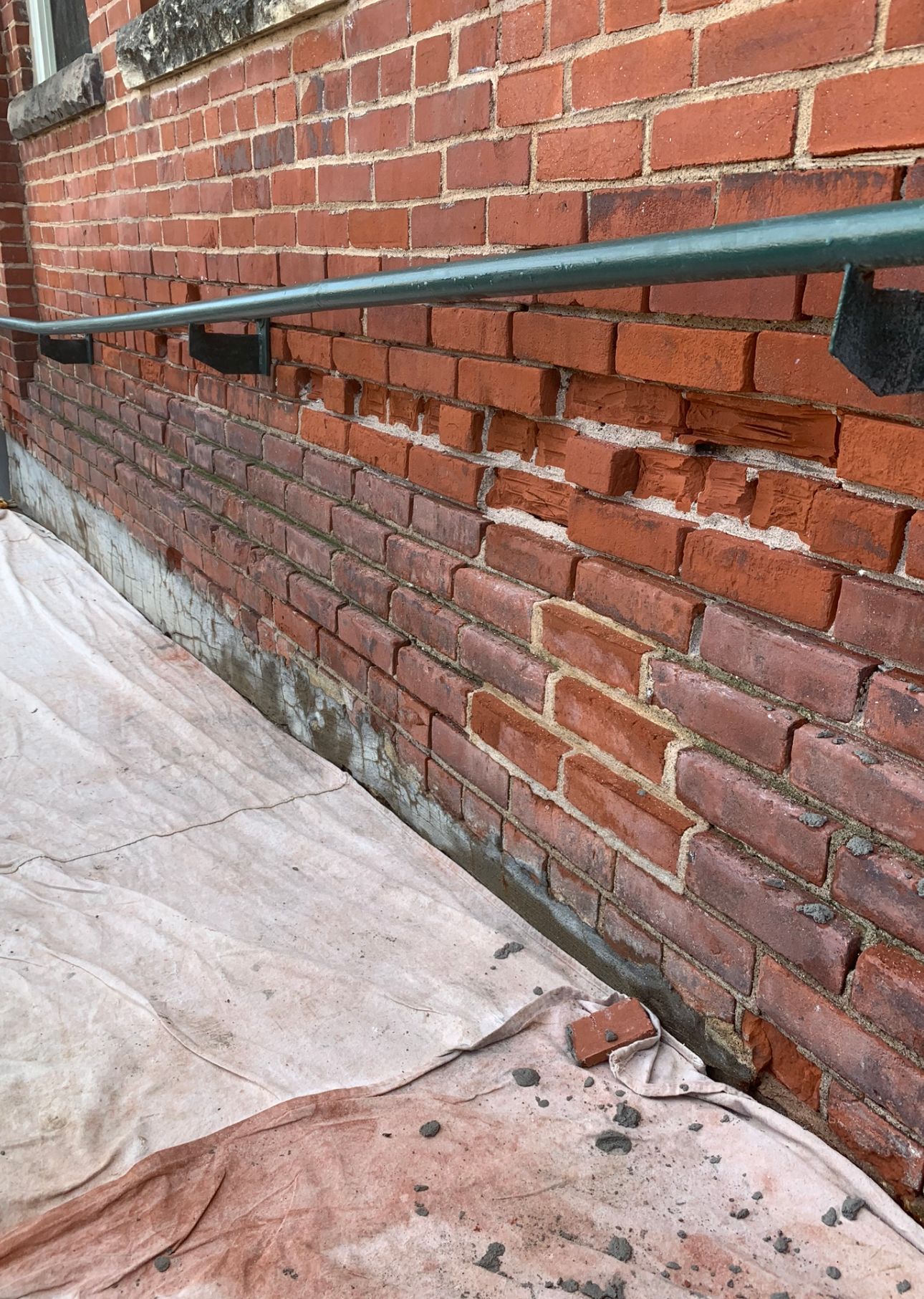 A close up of a brick wall with a rope hanging from it.