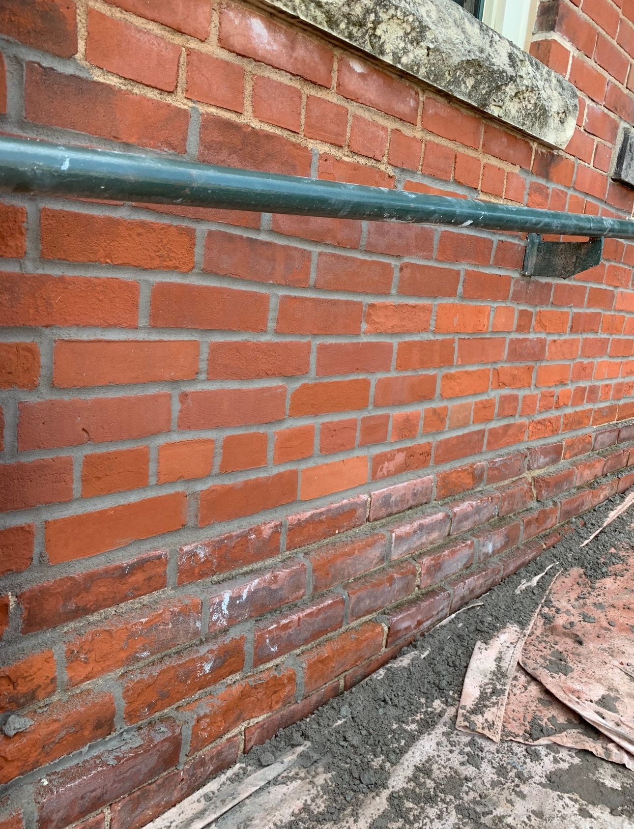 A close up of a brick wall with a green railing.