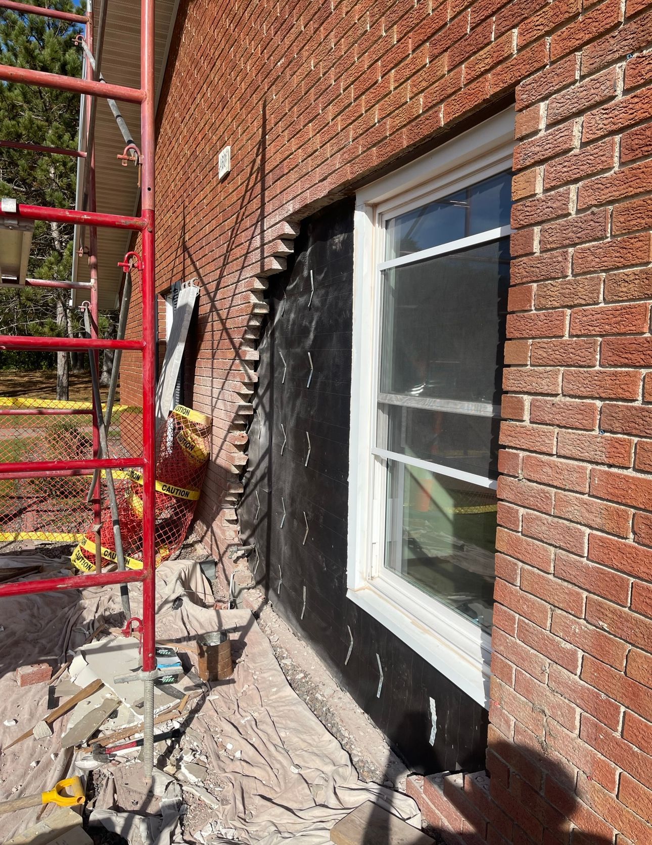 A brick building with a window and a scaffolding in front of it