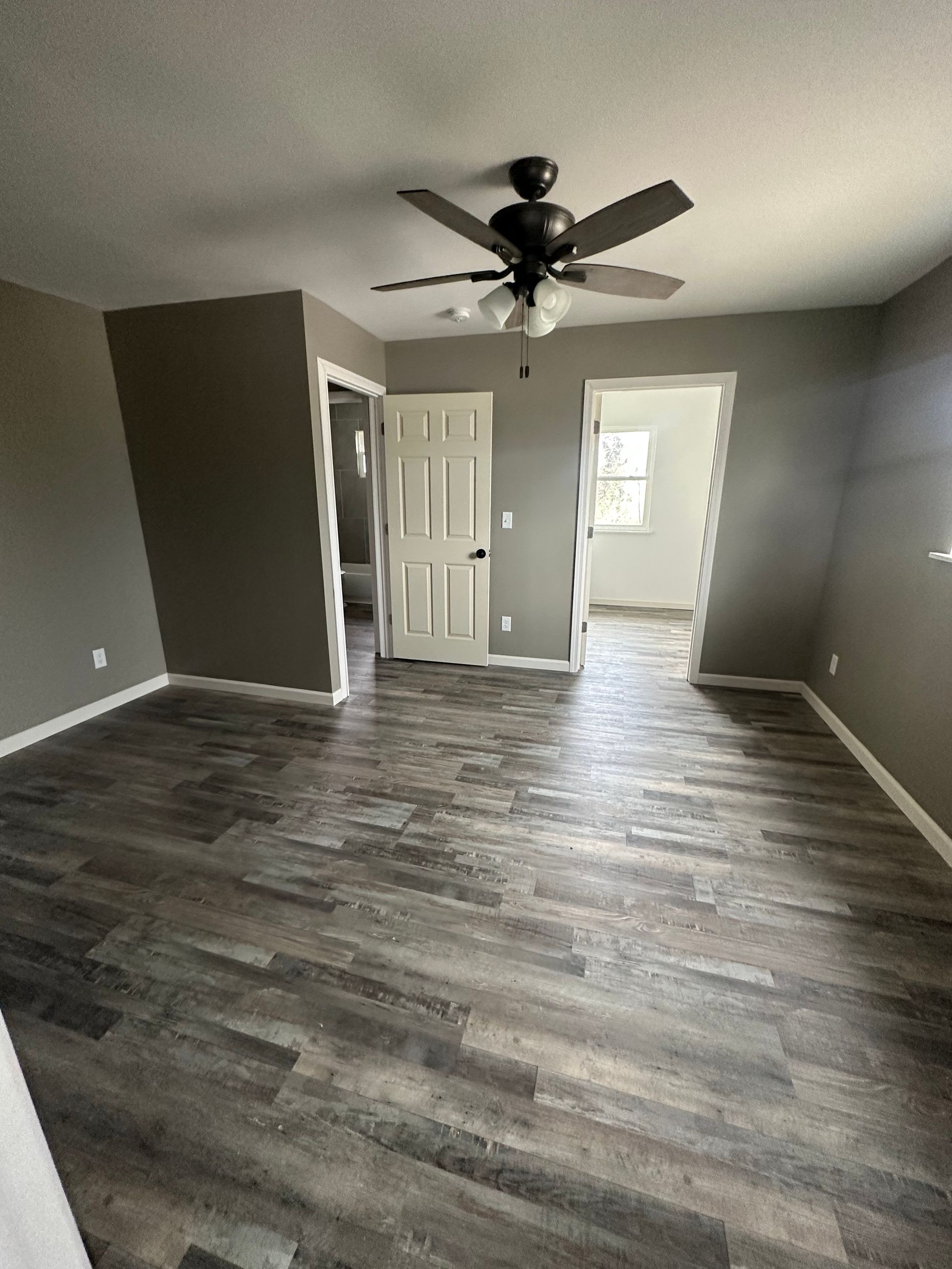 An empty room with a ceiling fan and wooden floors