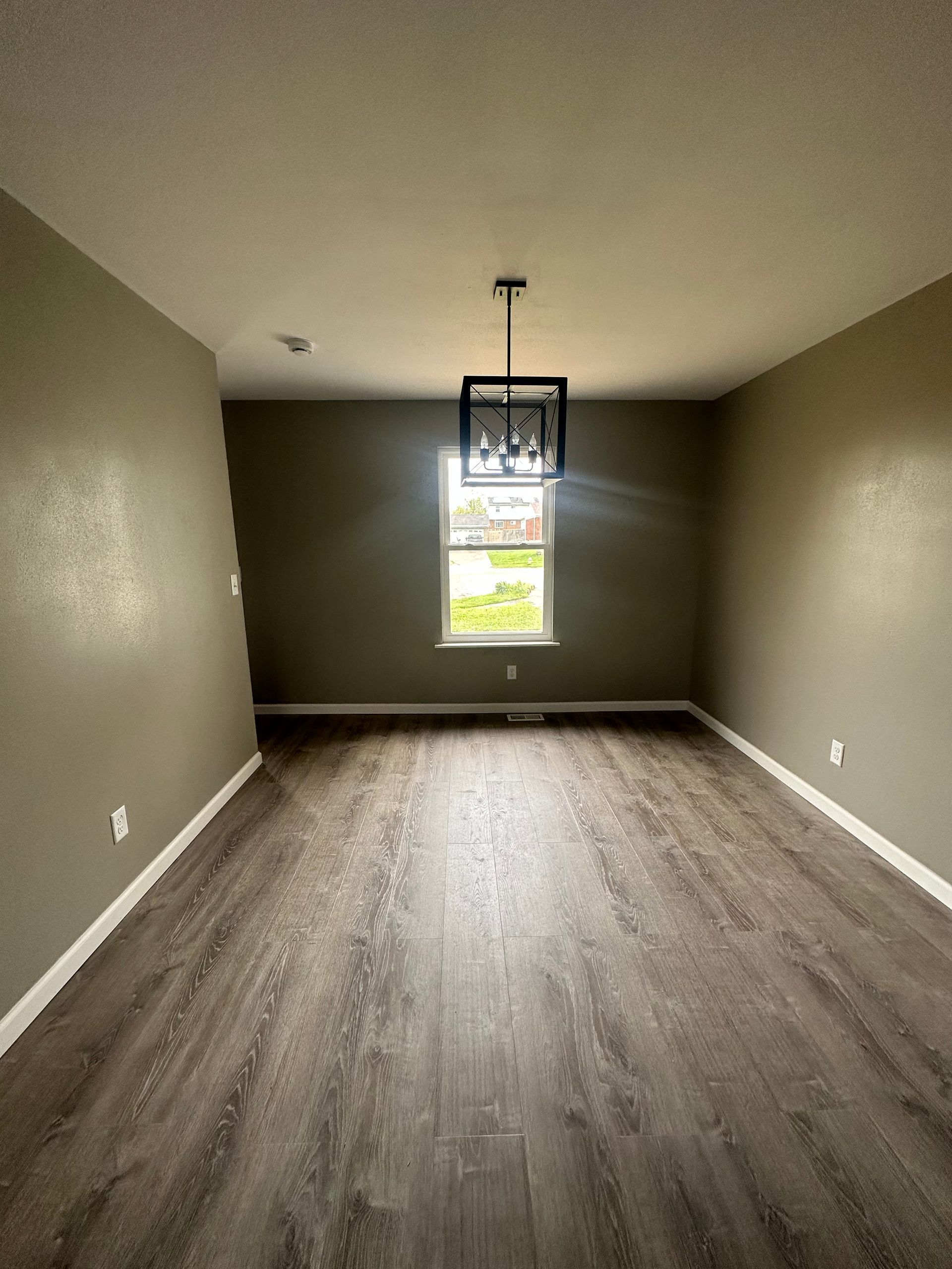 An empty room with hardwood floors and a window.