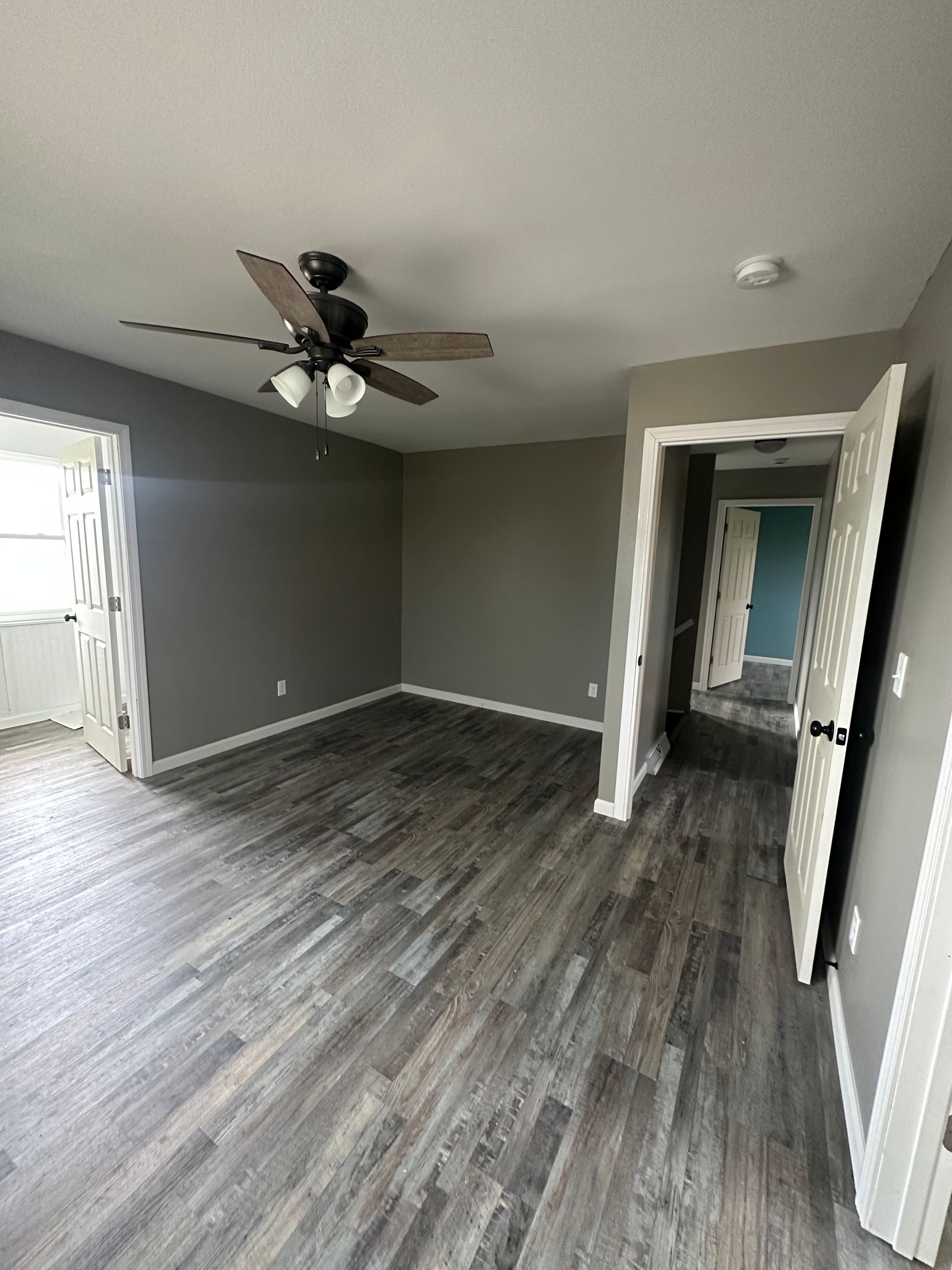 An empty room with a ceiling fan and hardwood floors.