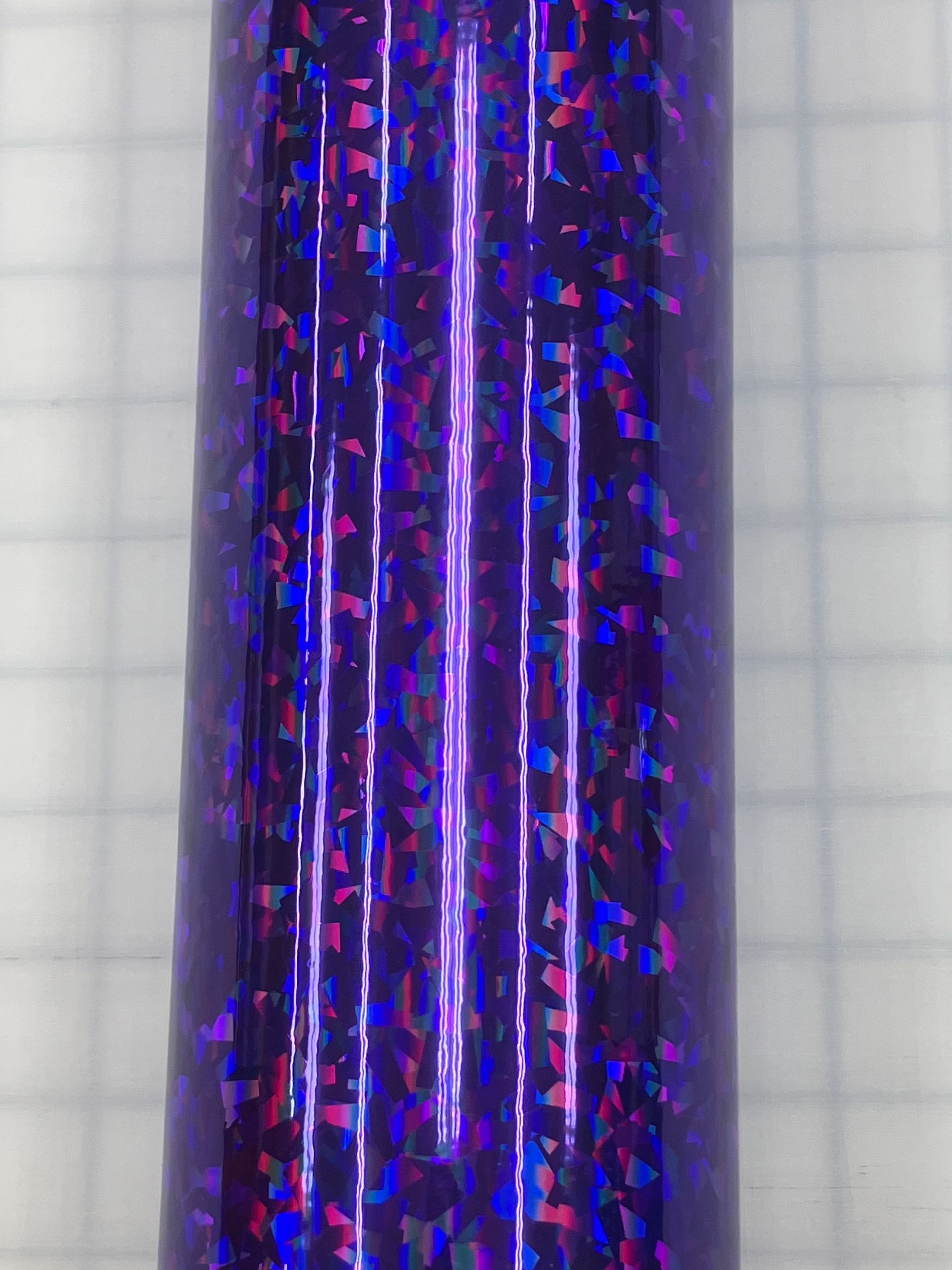 Close-up of a purple glittery cylindrical object on a light grid background