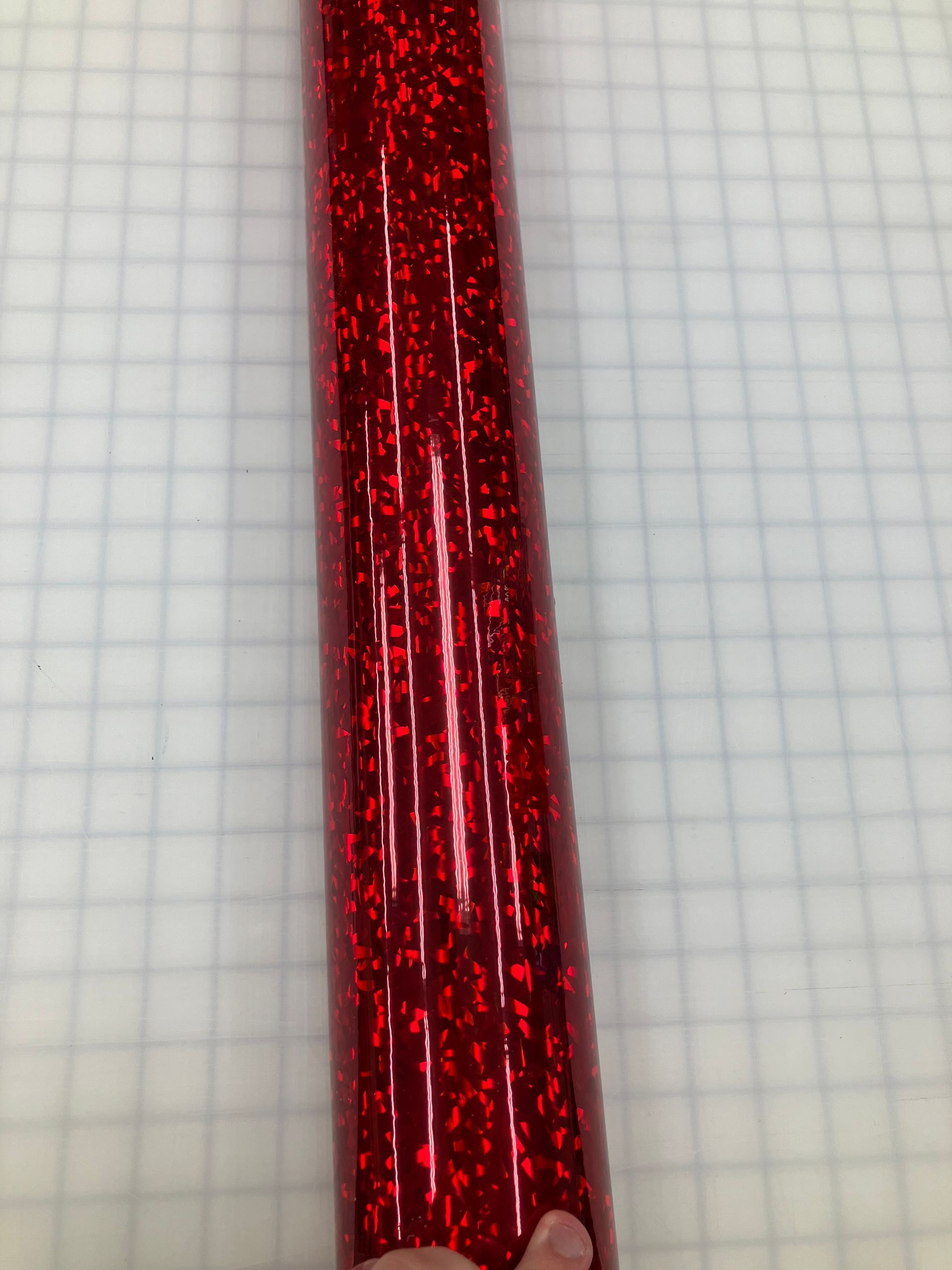 Red glittery cylindrical object on graph paper background