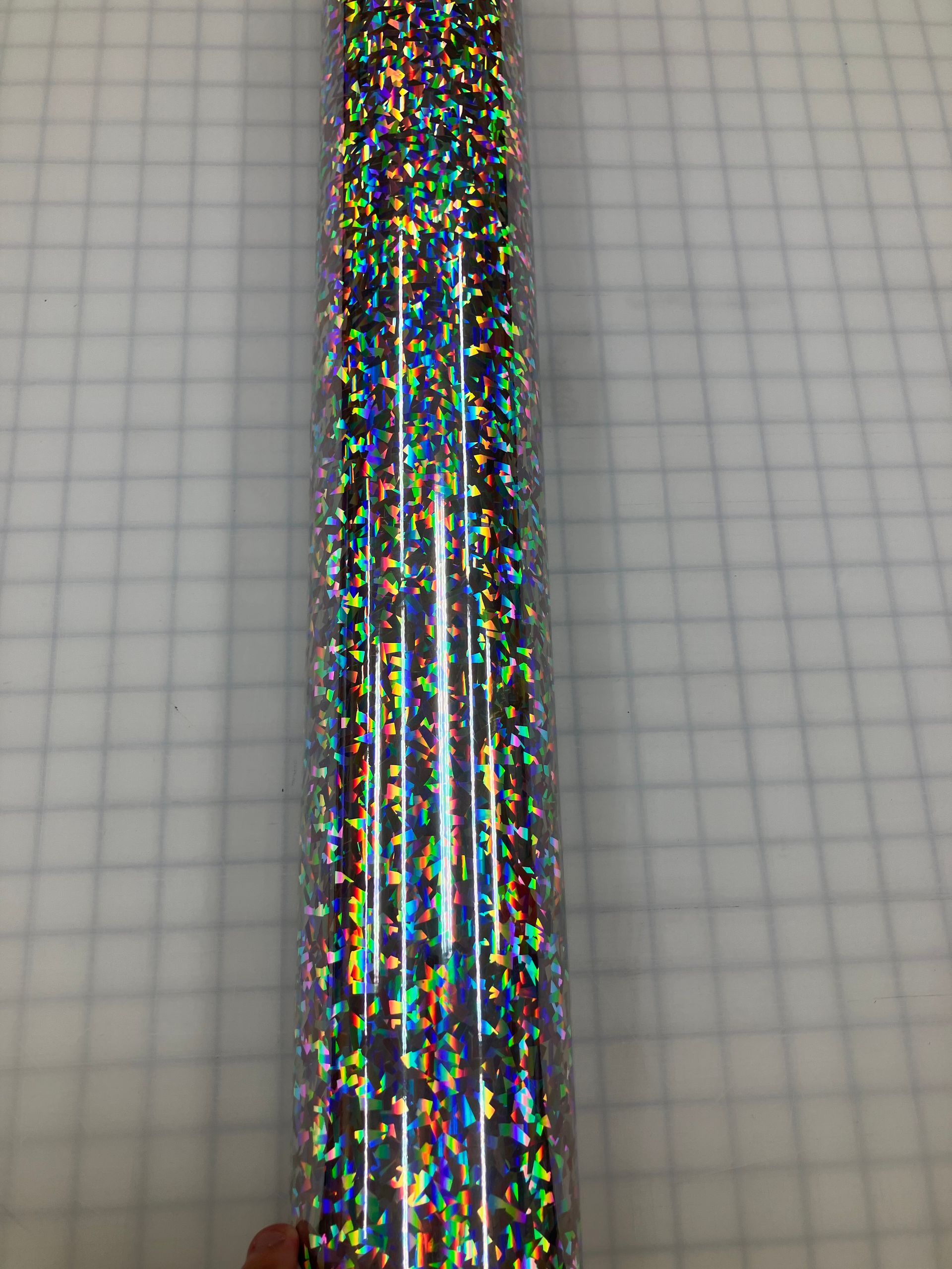 A glittery multicolored pen or tube on graph paper background