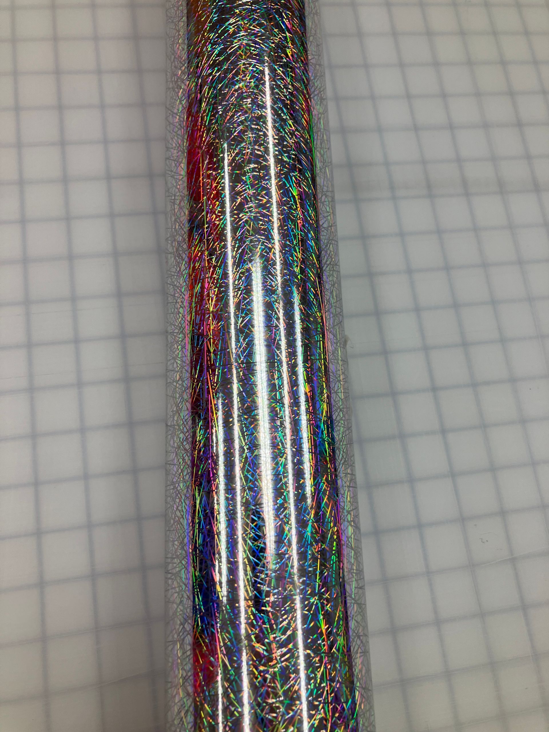 Shiny iridescent metallic pen or tube on graph paper background