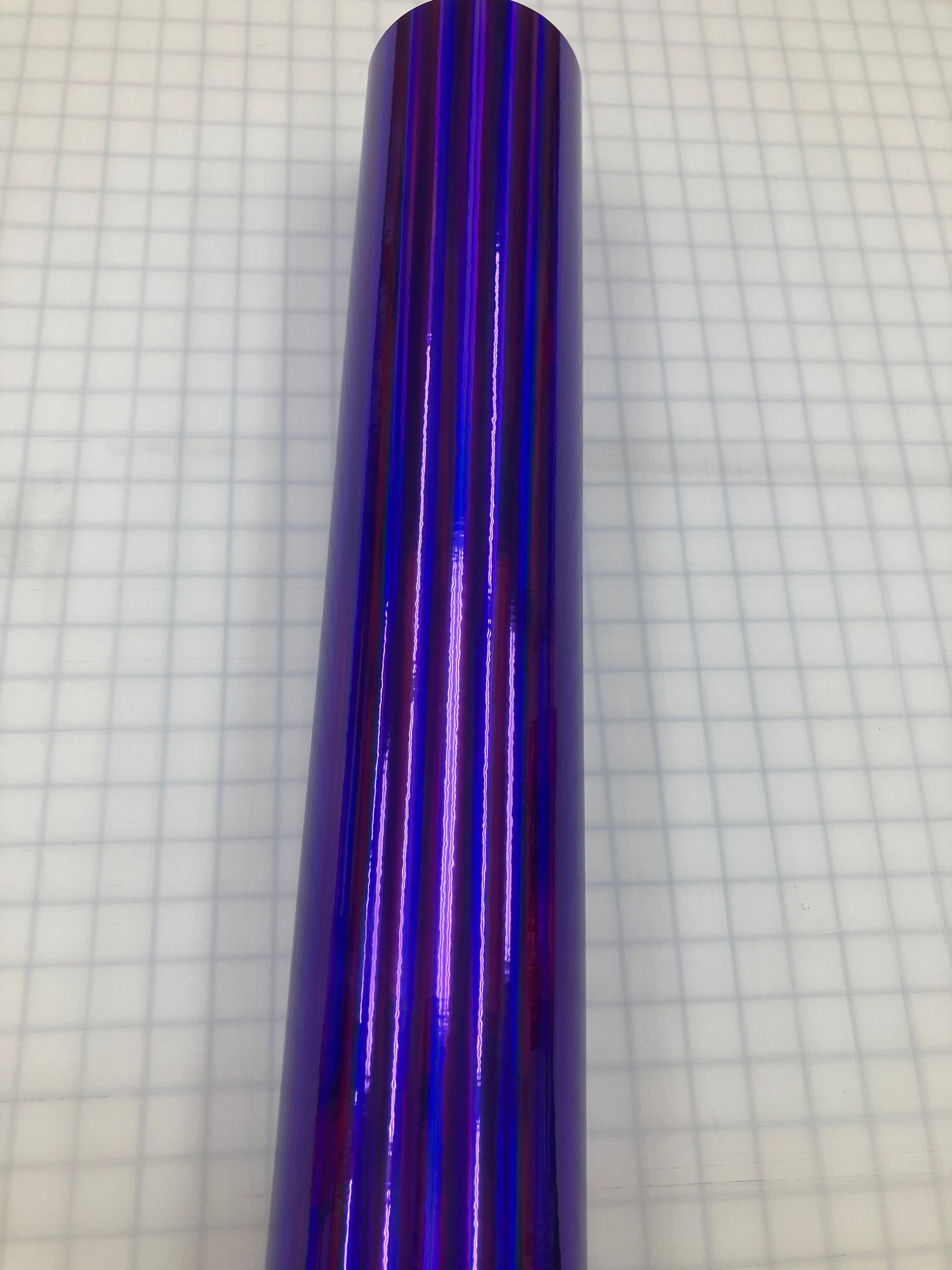 Shiny purple metallic cylinder on graph paper
