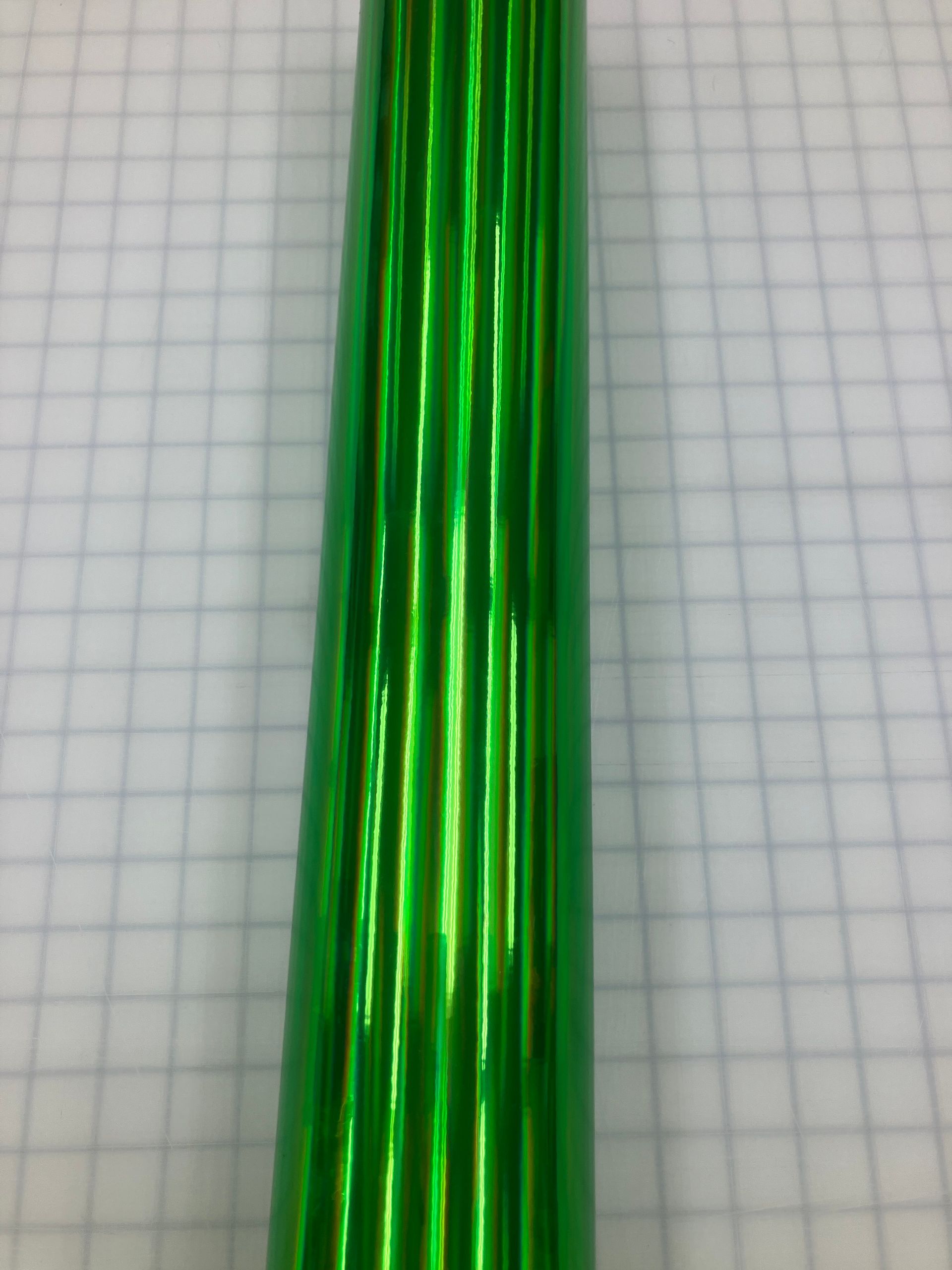 Close-up of shiny green metallic rods on a graph paper background