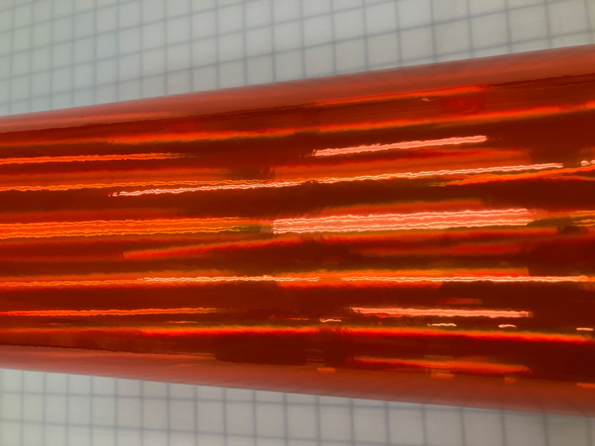 Close-up of translucent orange-red corrugated plastic or glass with horizontal ridges