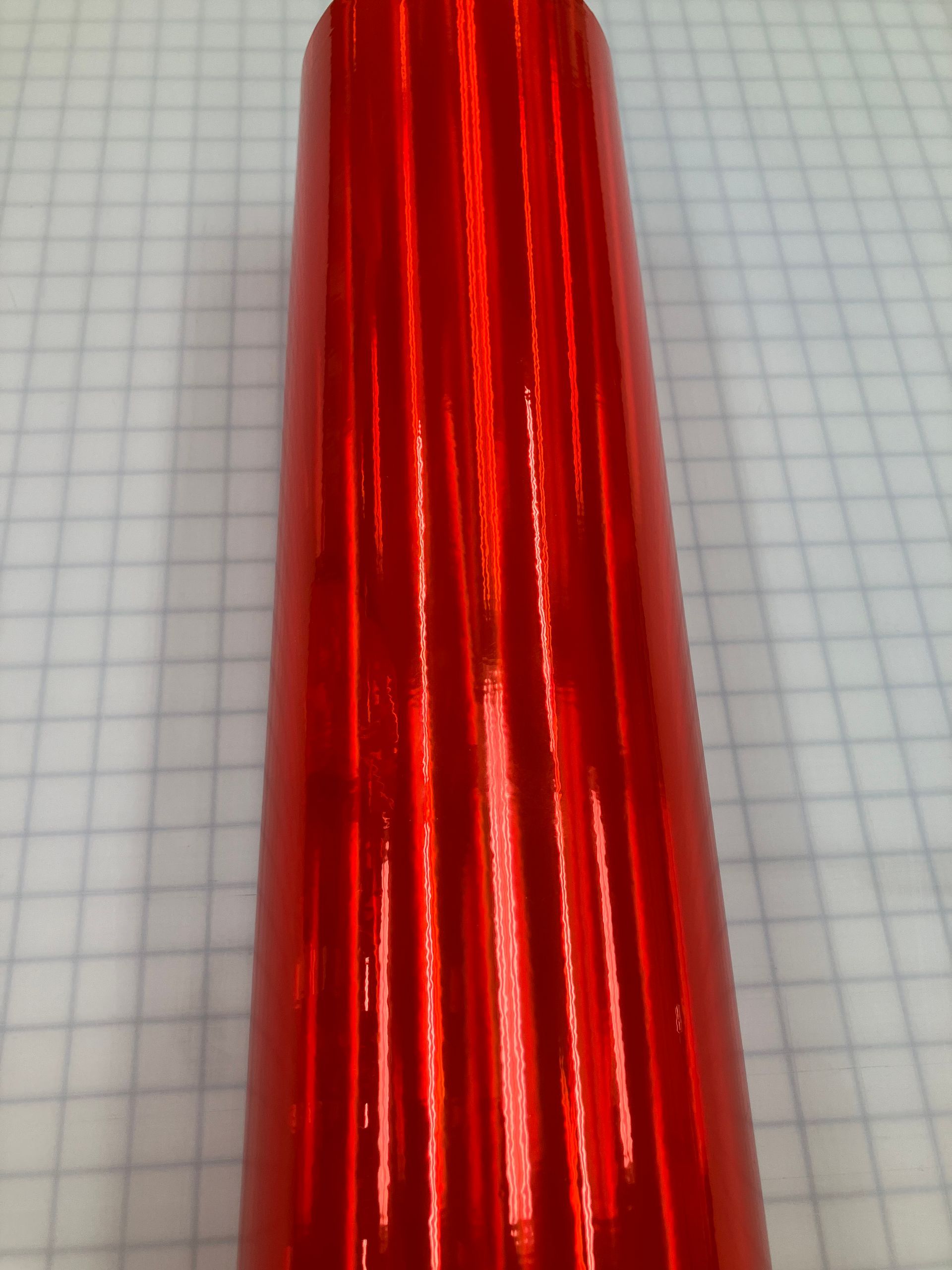 Shiny red metallic cone-shaped object on graph paper background