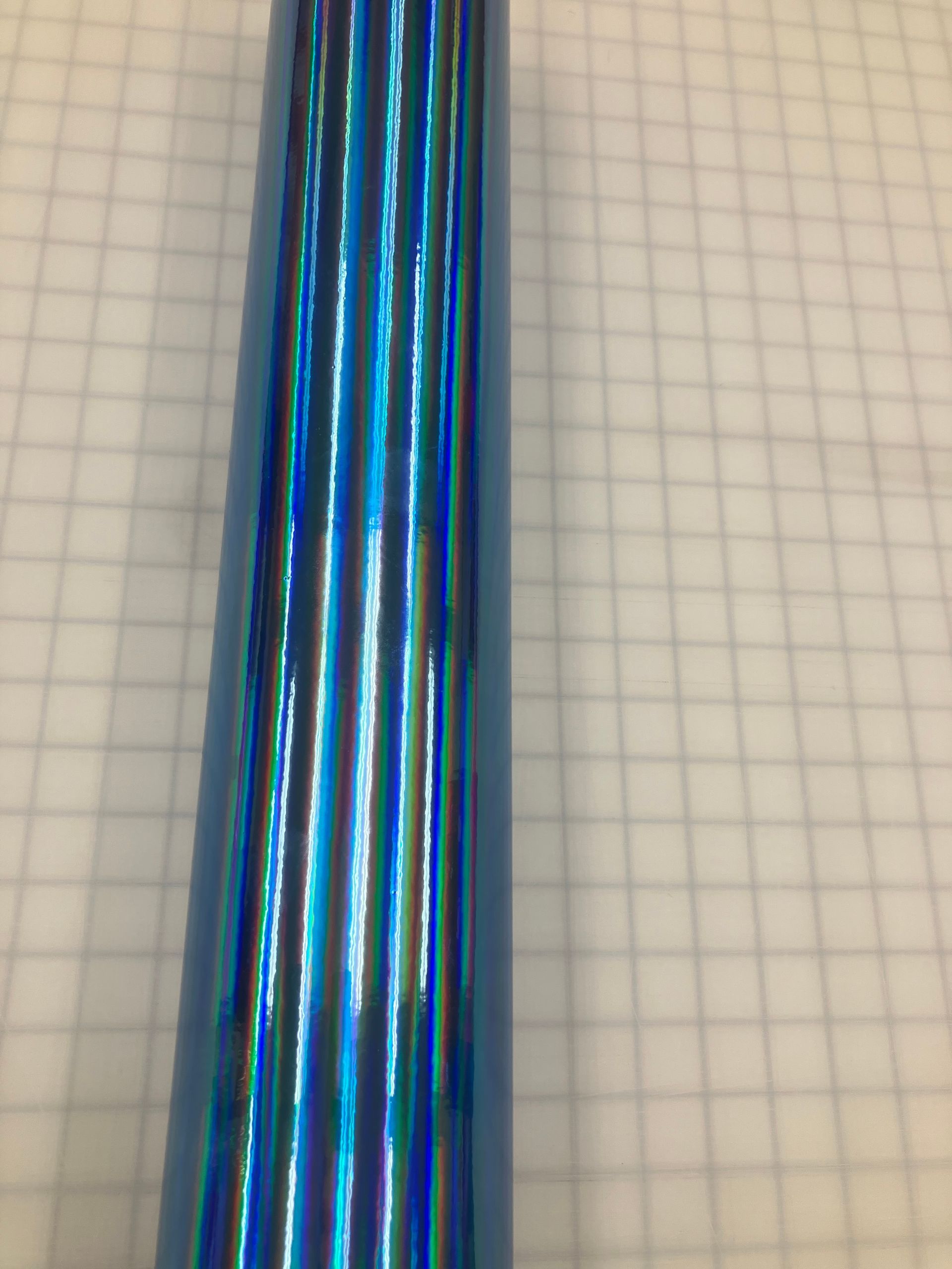 Blue iridescent metallic tube on graph paper background