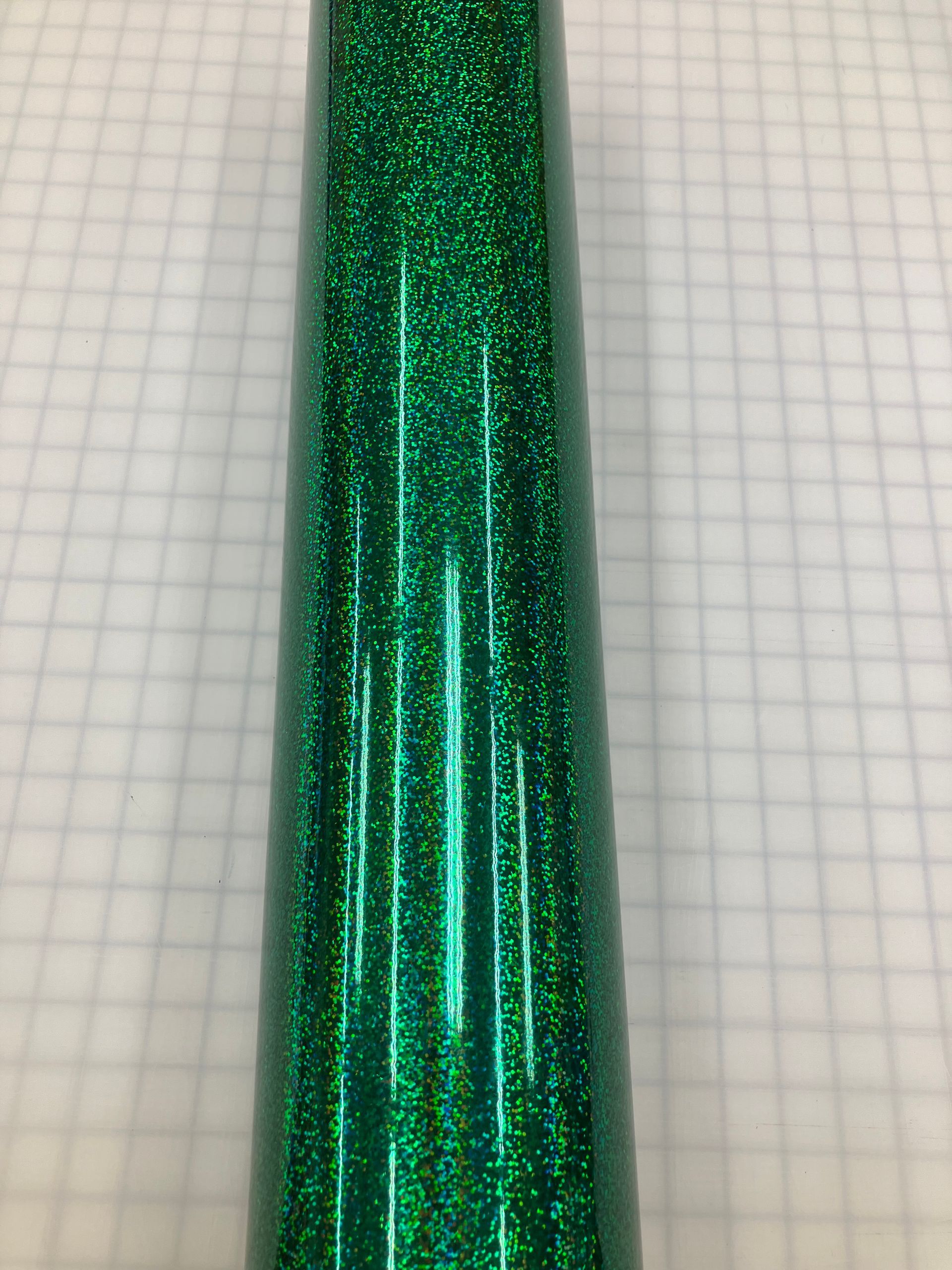 Close-up of a glittery green metallic tube on graph paper