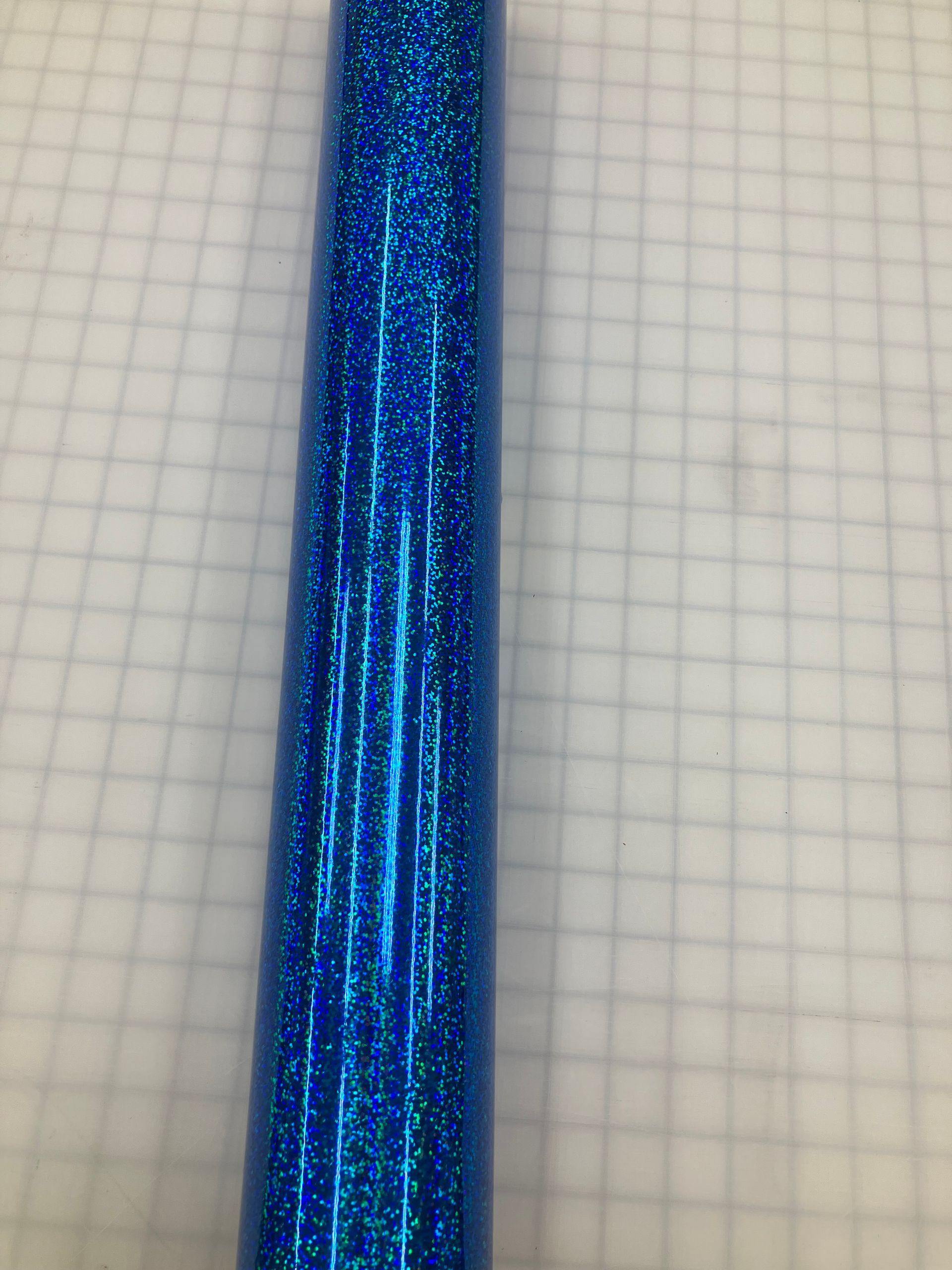 Close-up of a shiny blue glittery fabric or ribbon on graph paper.