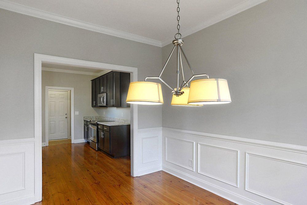 An empty dining room with hardwood floors and a chandelier hanging from the ceiling.
