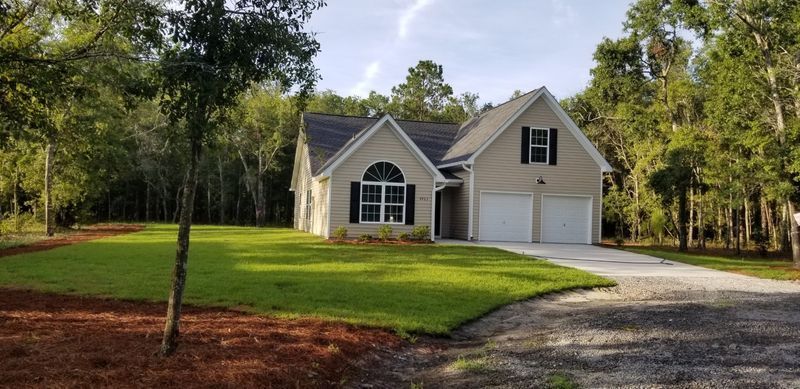 A large house with two garages is surrounded by trees and grass.