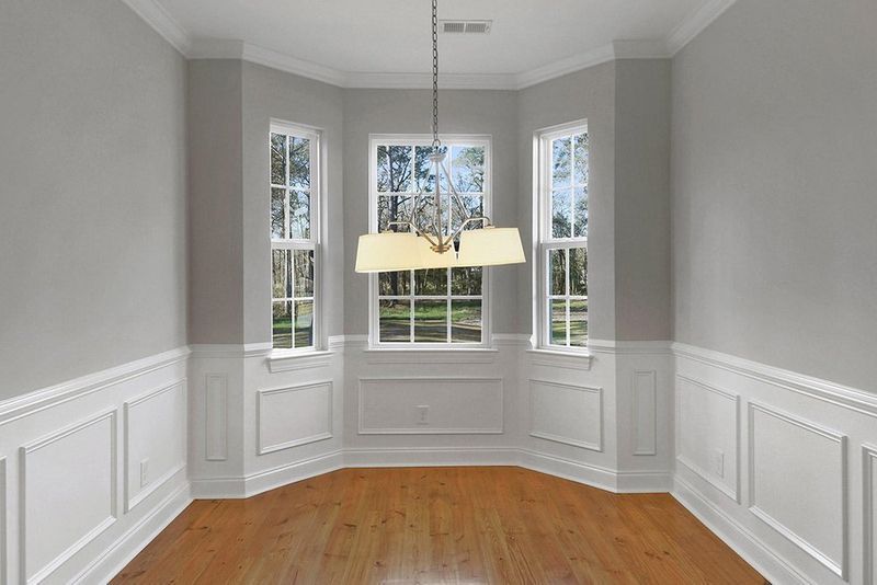 An empty dining room with hardwood floors and a chandelier hanging from the ceiling.
