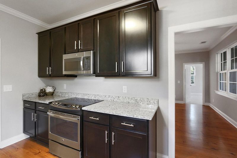A kitchen with black cabinets , stainless steel appliances , granite counter tops and a stove.
