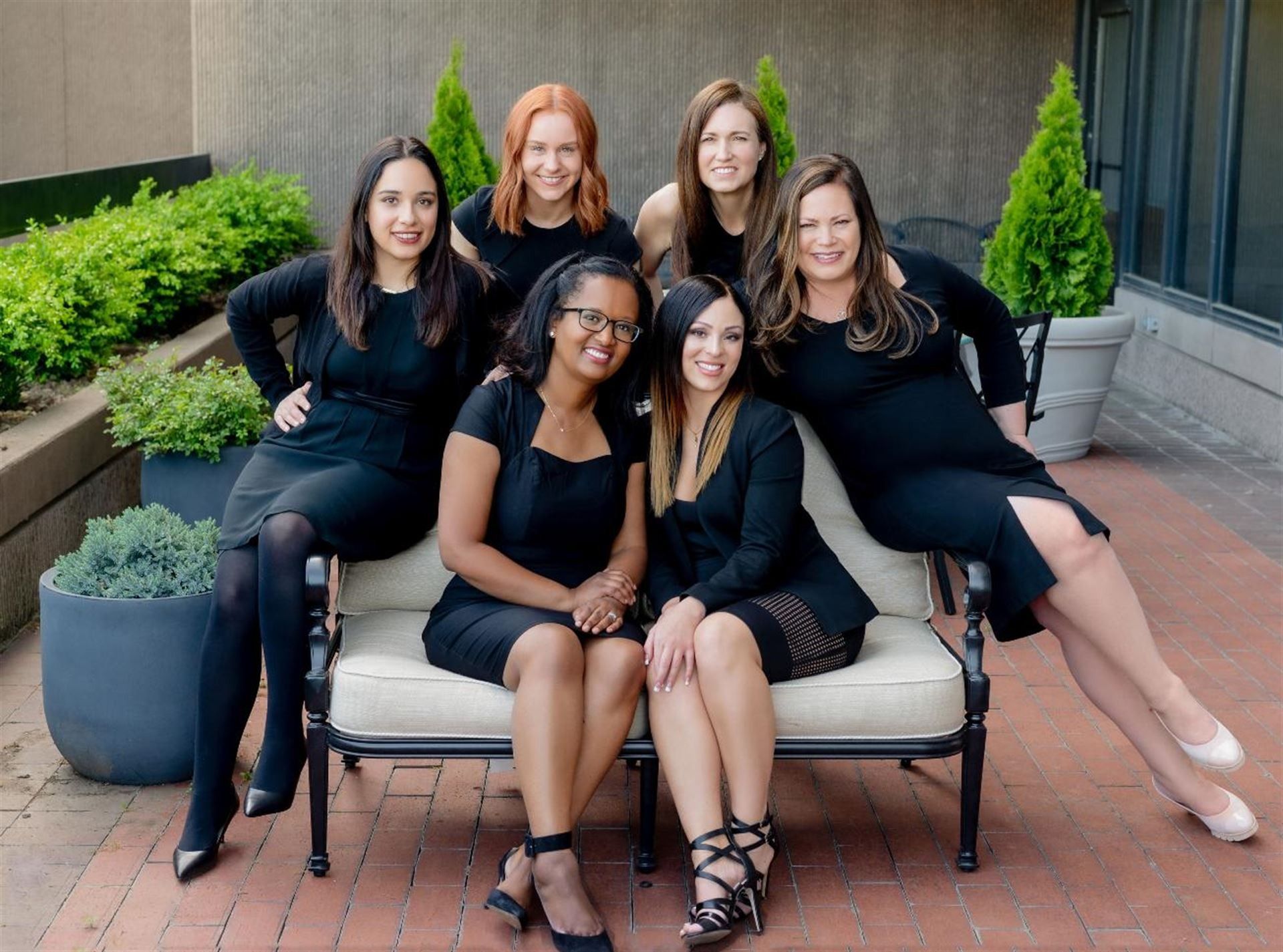 A group of women are posing for a picture while sitting on a couch.