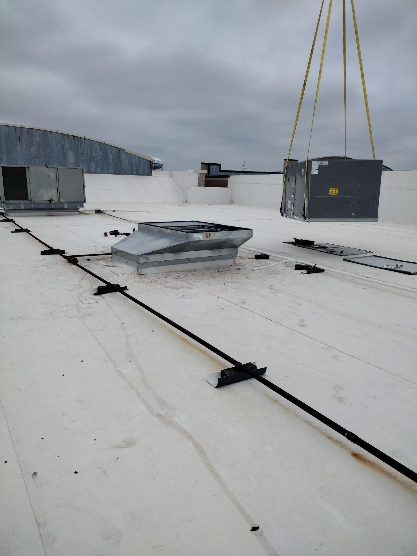 A crane is lifting a box on top of a white roof.