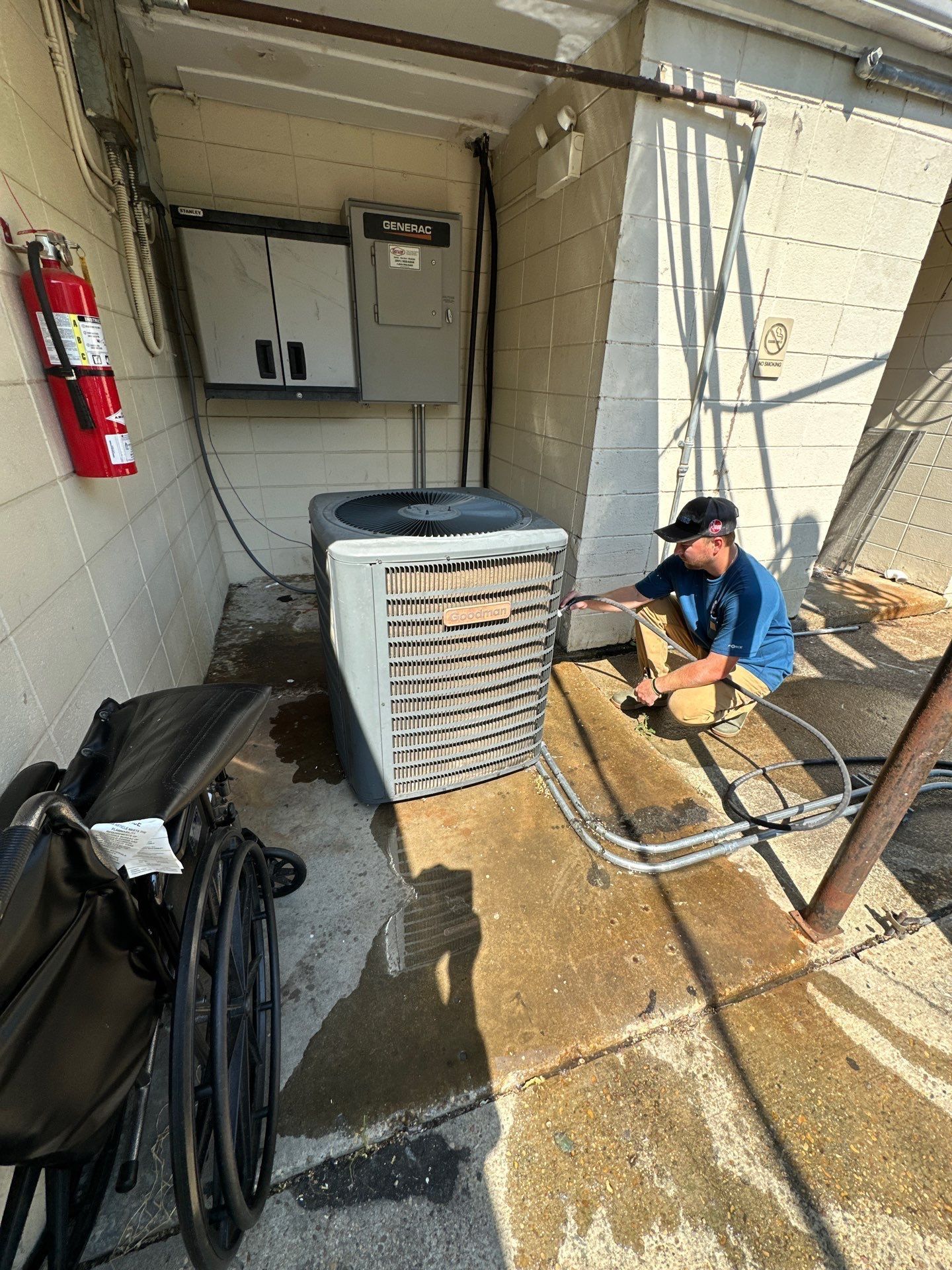 A man is working on an air conditioner in a building next to a wheelchair.