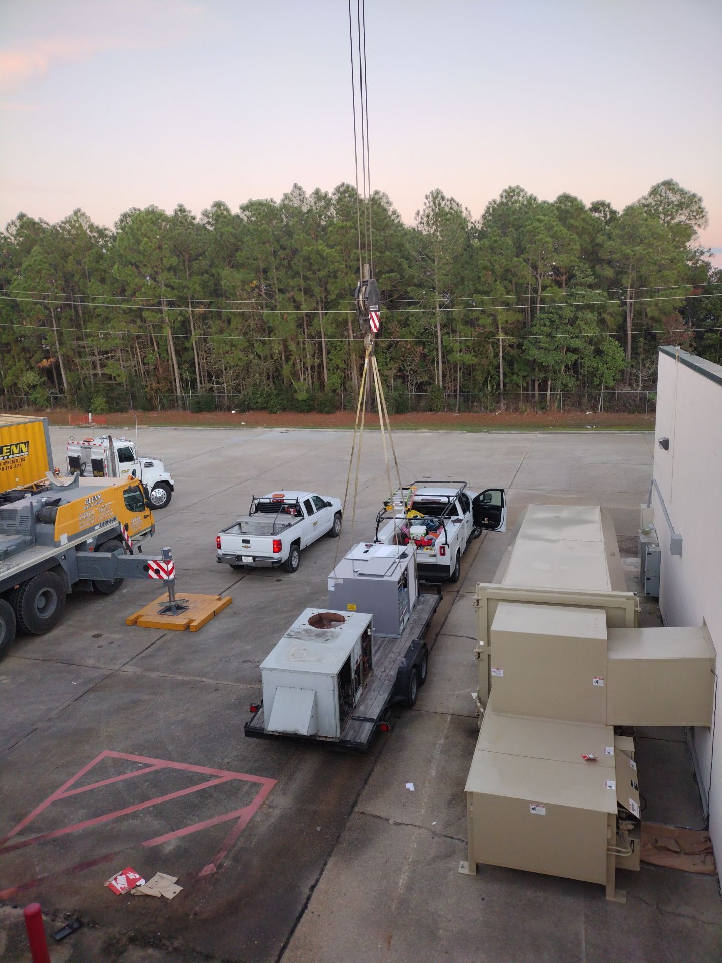 A truck is being lifted by a crane in a parking lot.