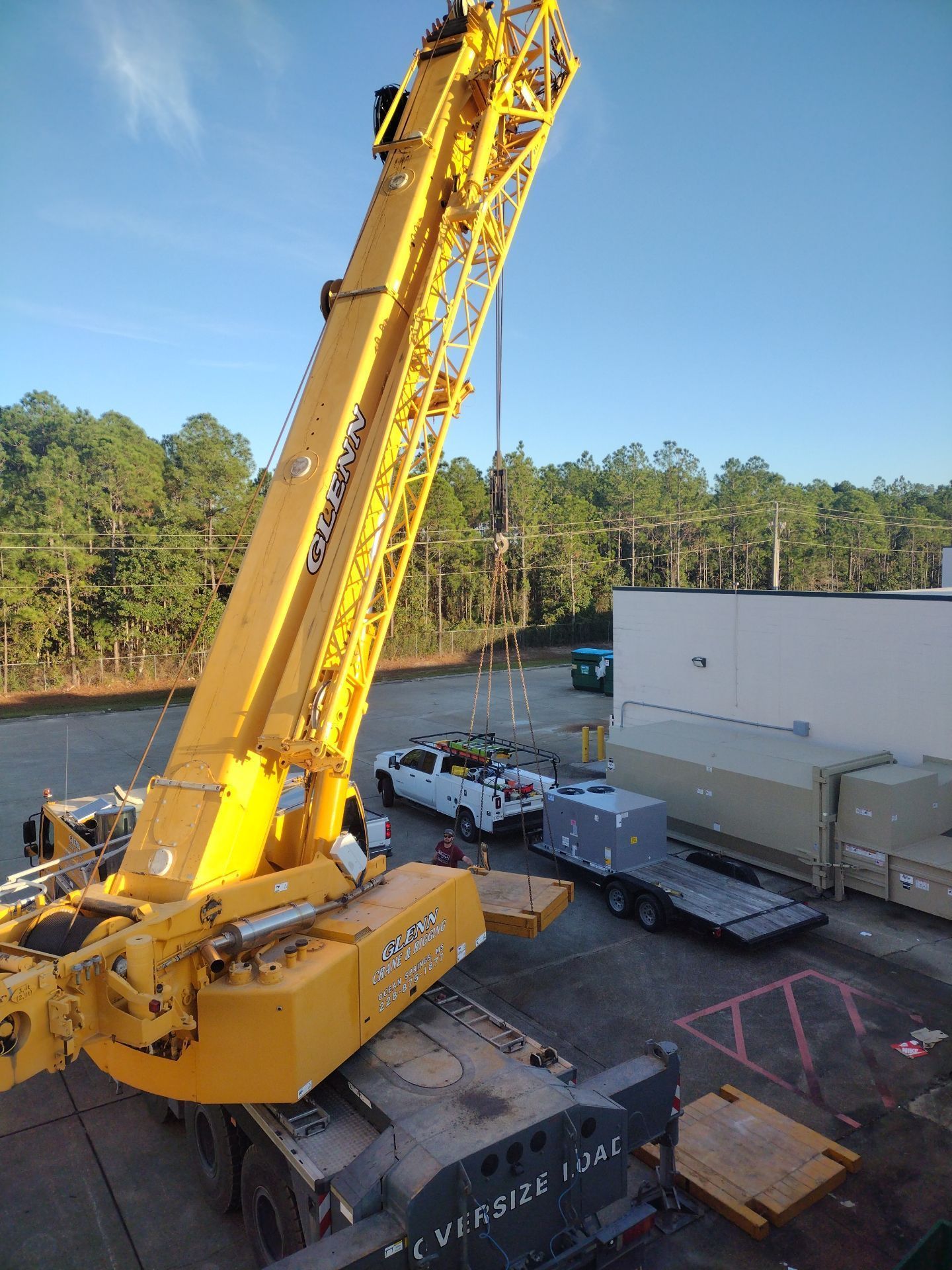 A large yellow crane is lifting a container in a parking lot.