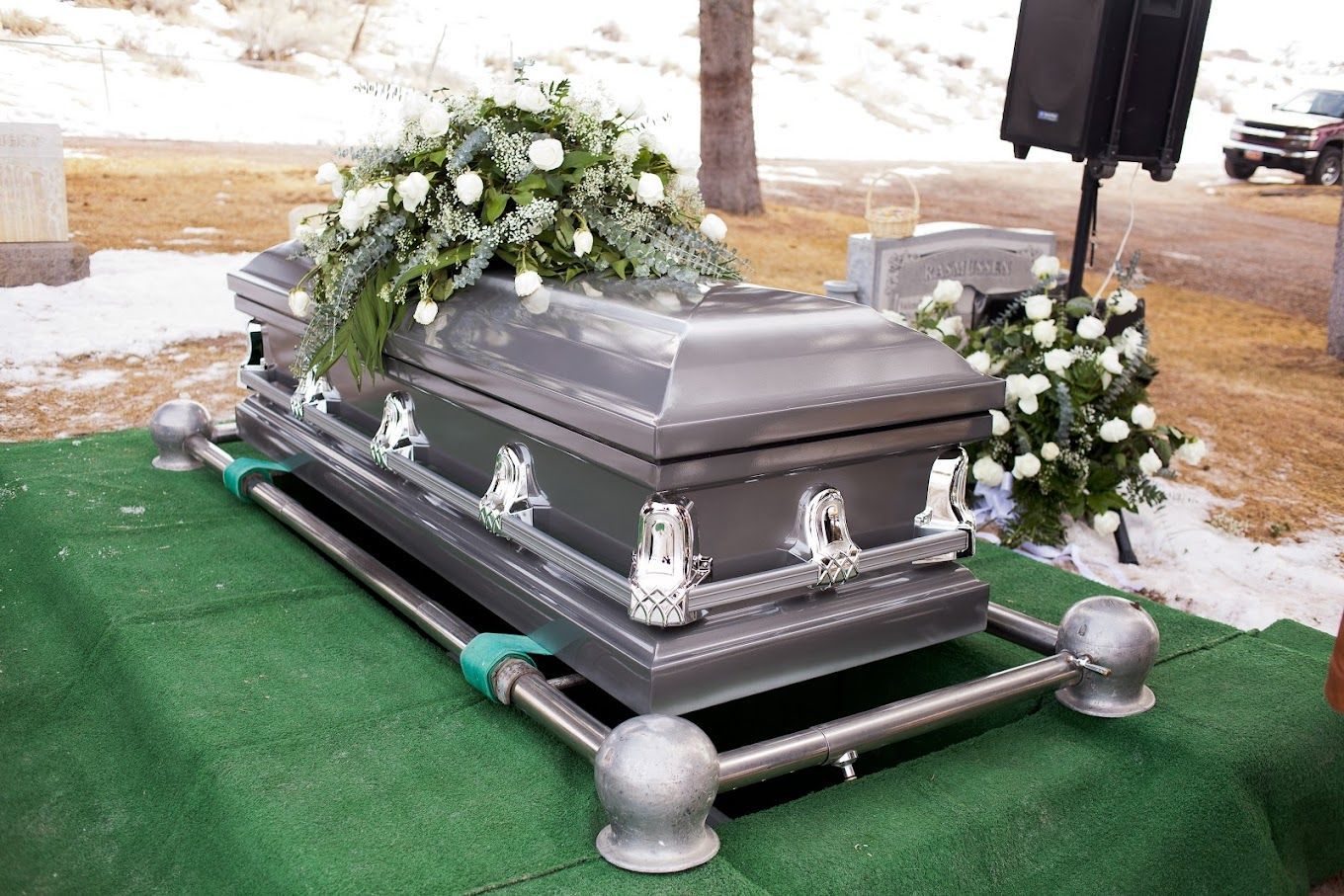 A silver coffin is sitting on top of a green carpet.