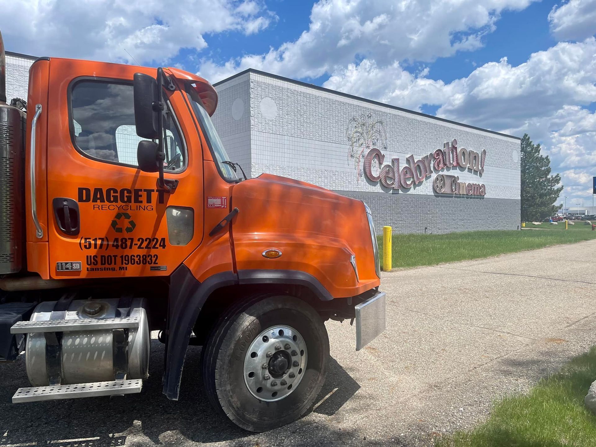 Orange DAGGETT truck parked beside a warehouse under a cloudy sky