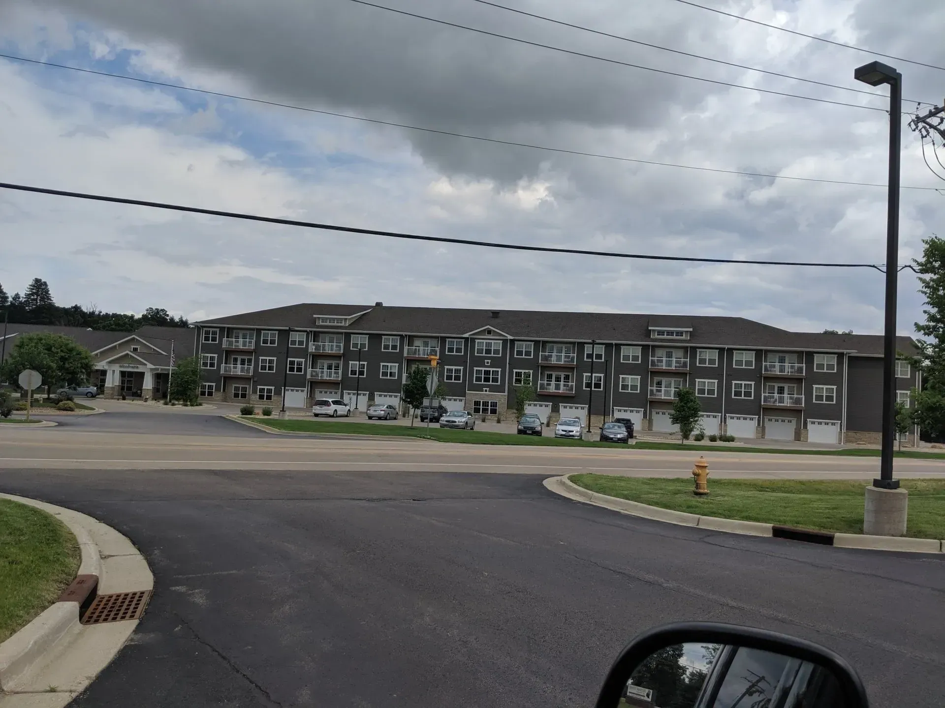 Multi-story apartment building with dark gray siding, cloudy sky.