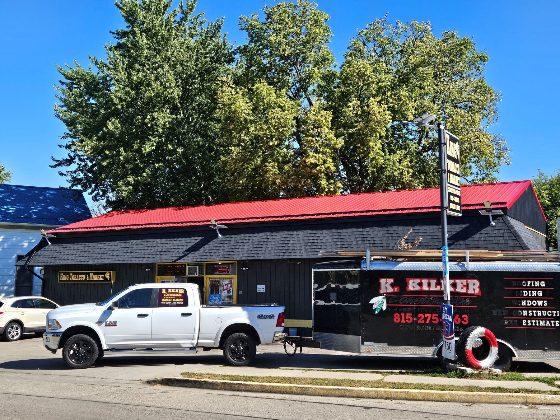 White truck and trailer in front of a building with a red roof; signage for 