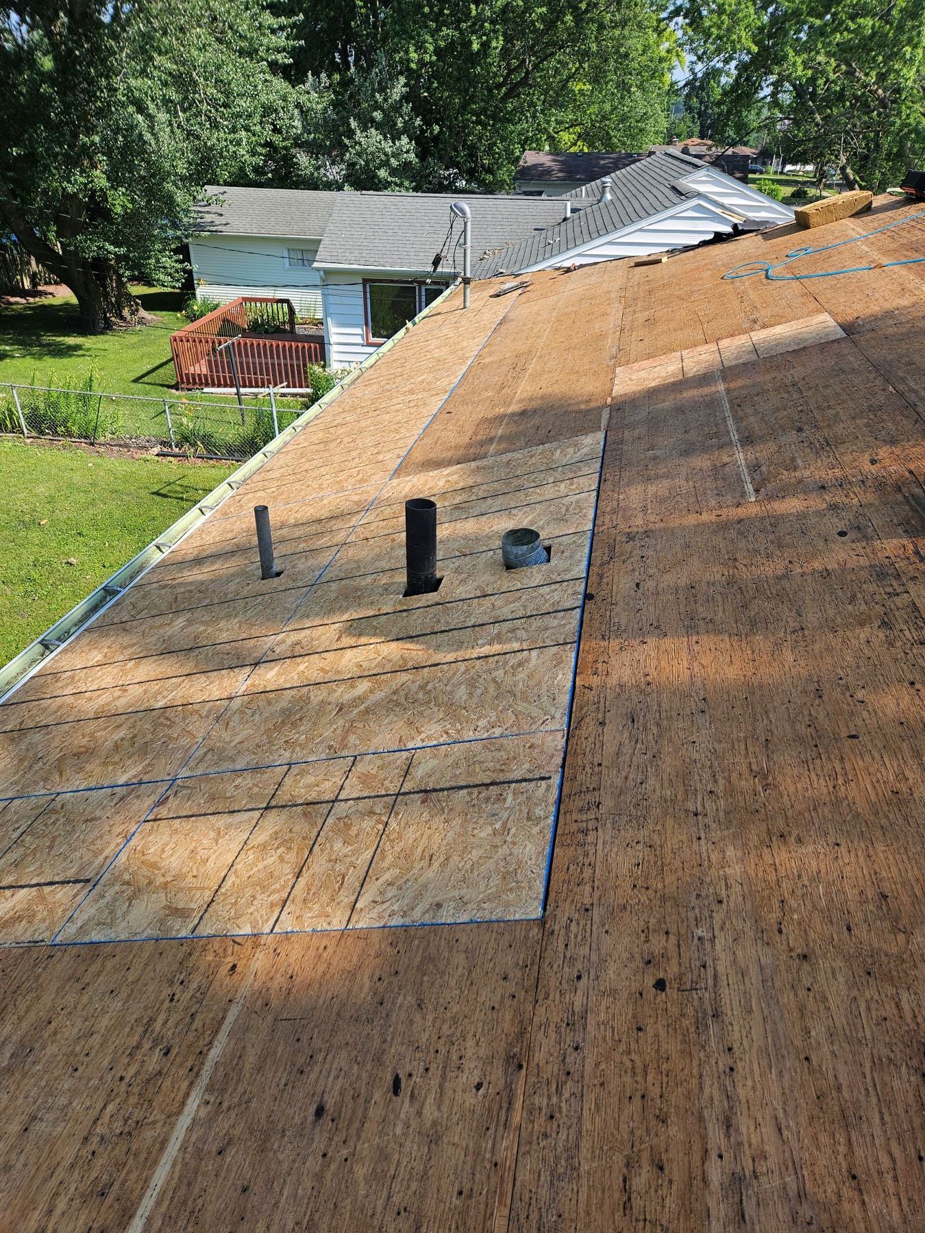 Roof with exposed sheathing, plumbing vents, and partial asphalt shingle installation.