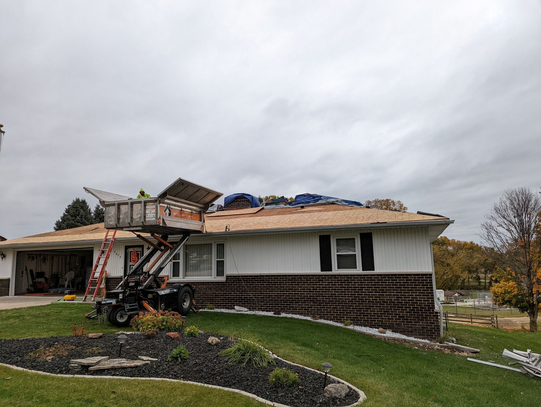 Roof being replaced on a house; a lift is used to bring materials up to the roof.