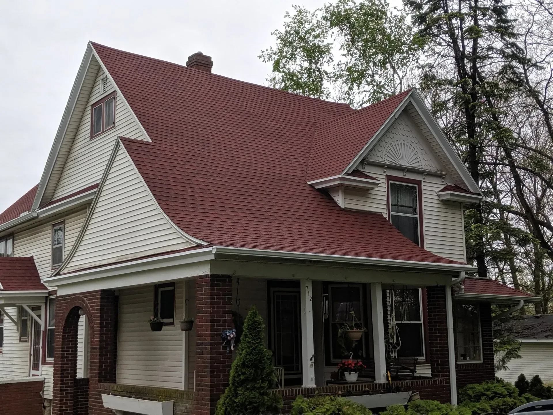 Two-story house with a red roof, white siding, and a covered porch.