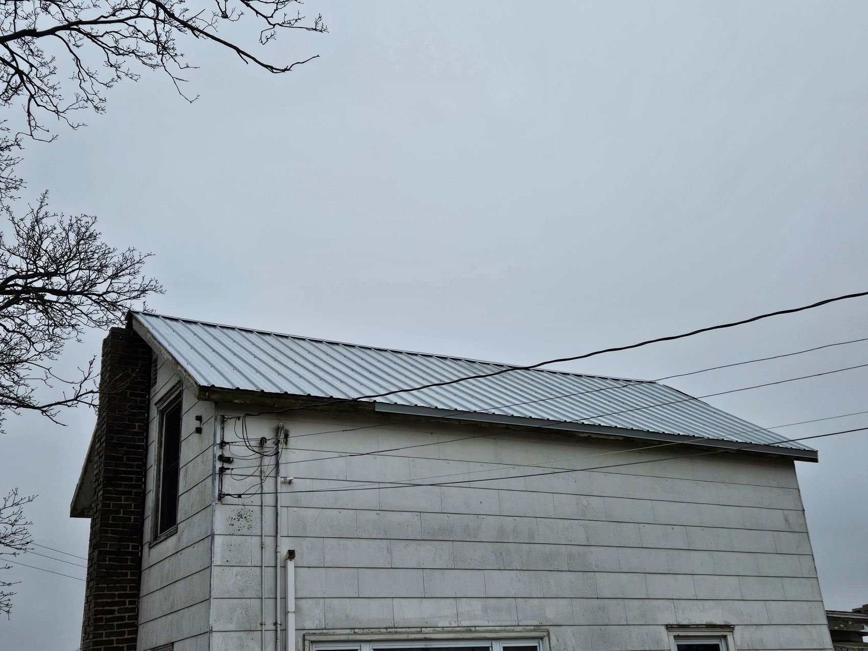 White house with a metal roof under an overcast sky.