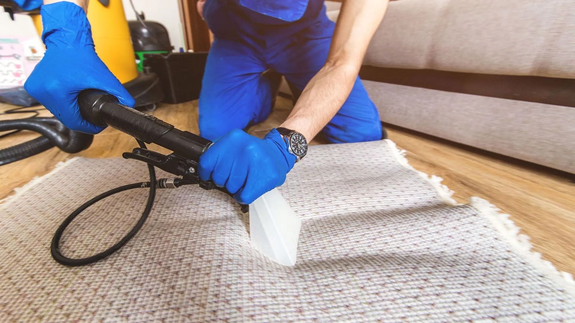 A man is cleaning a carpet with a vacuum cleaner.