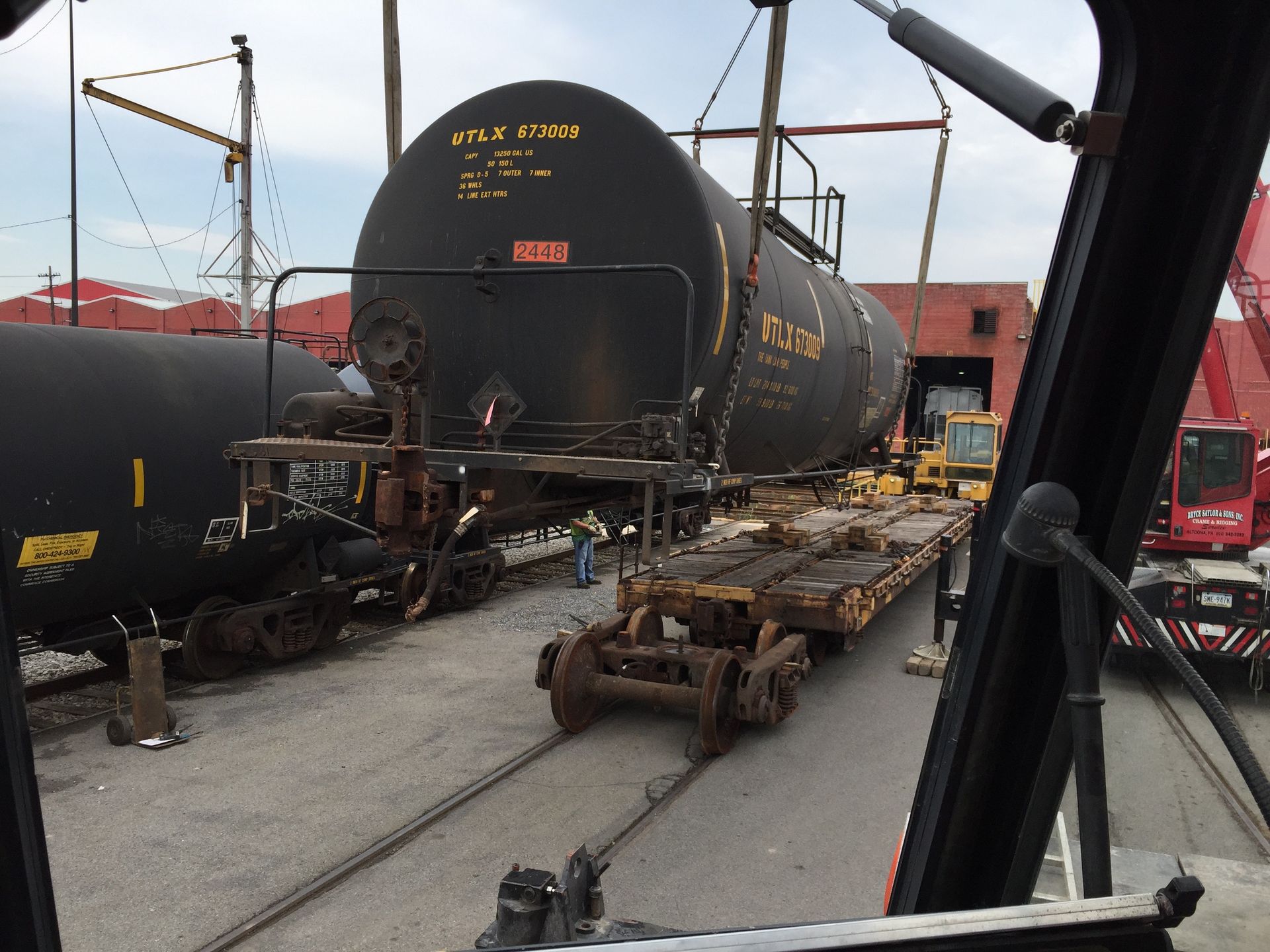 Rail yard with a black tanker railcar and maintenance equipment on tracks