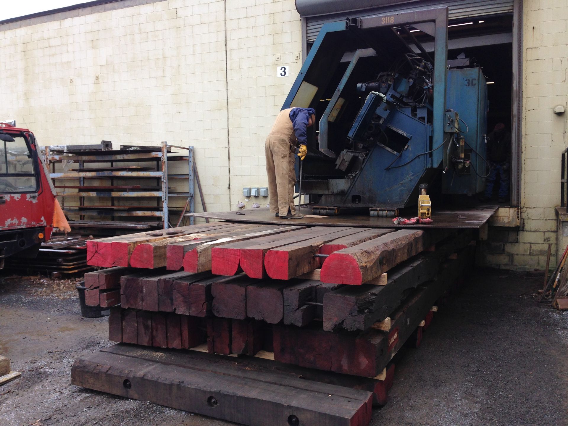 Worker loading machinery onto a flatbed truck at a warehouse loading dock