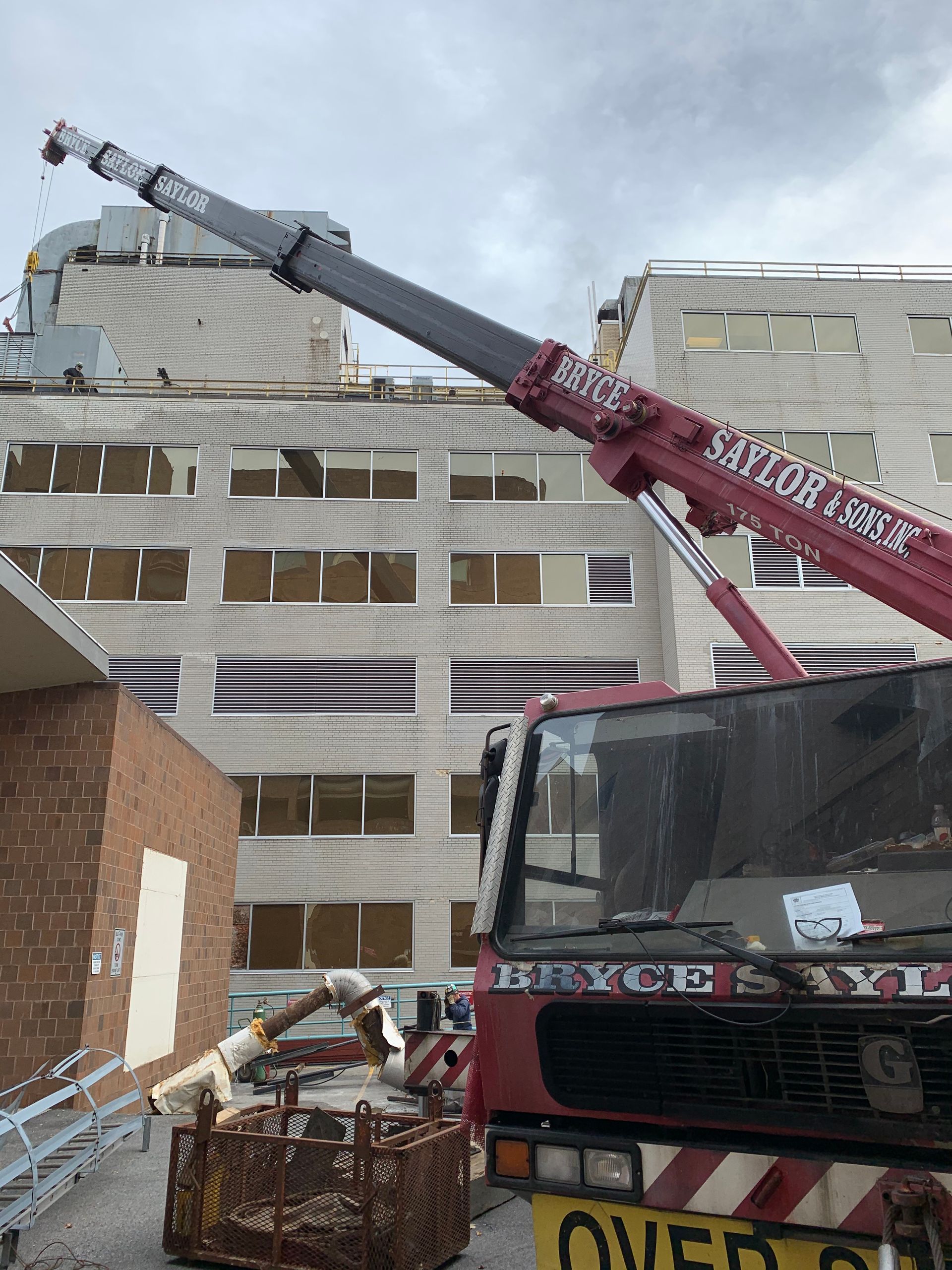 Crane lifting debris beside a partially demolished building, with a truck in the foreground.