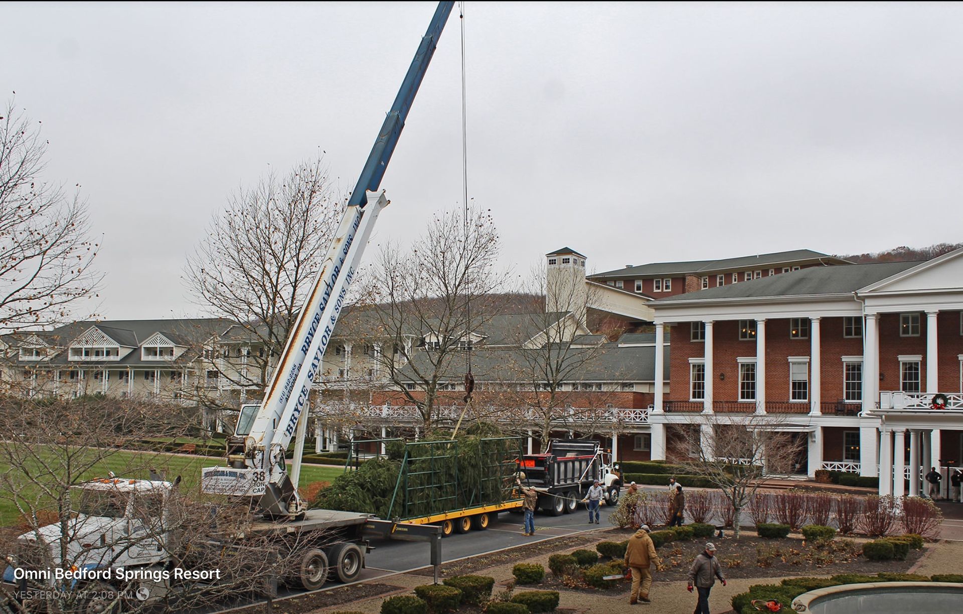 Crane lifting equipment beside a brick building with columns in an overcast outdoor setting