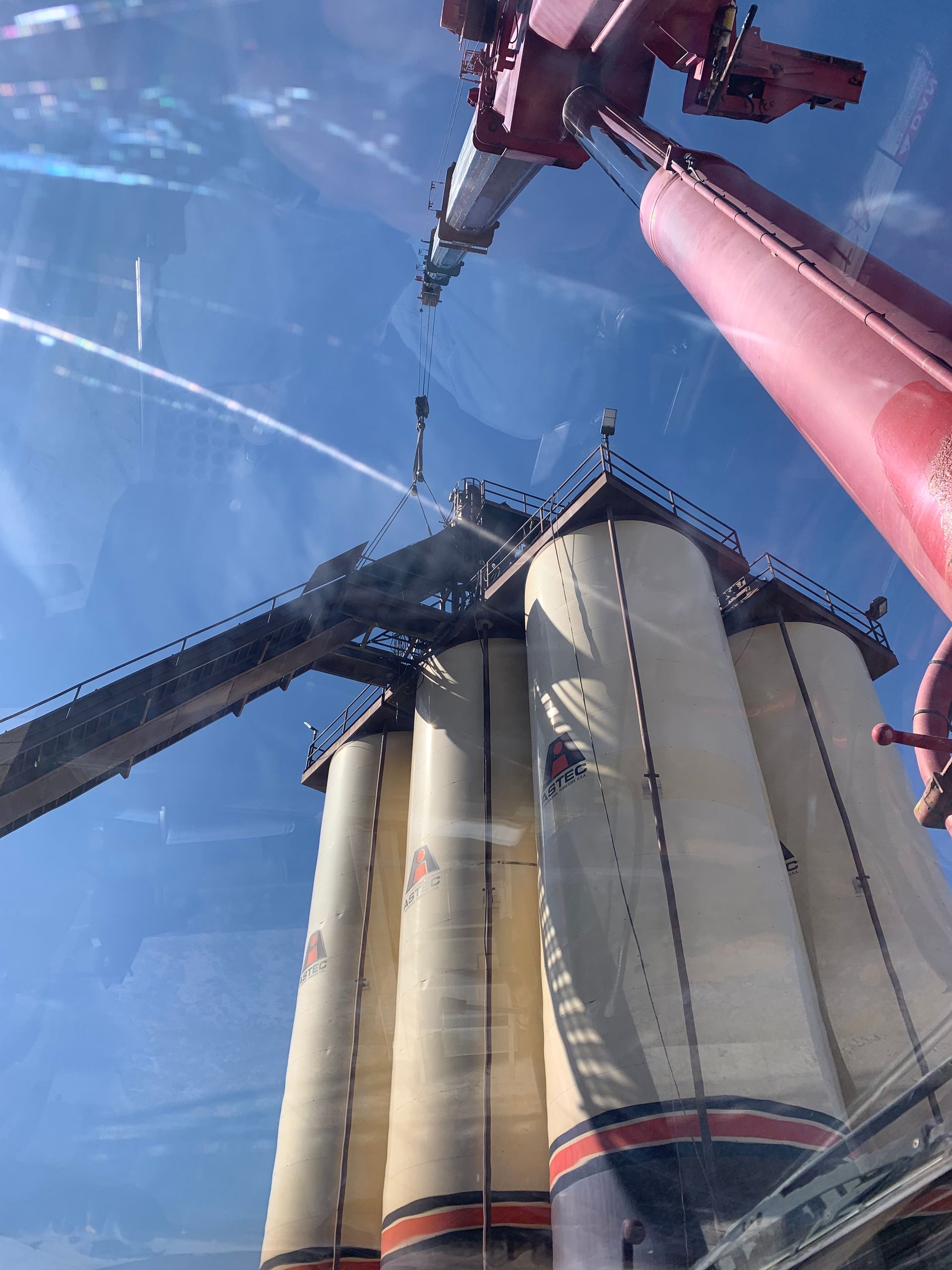 Industrial machinery and tall silos against a blue sky, viewed from below