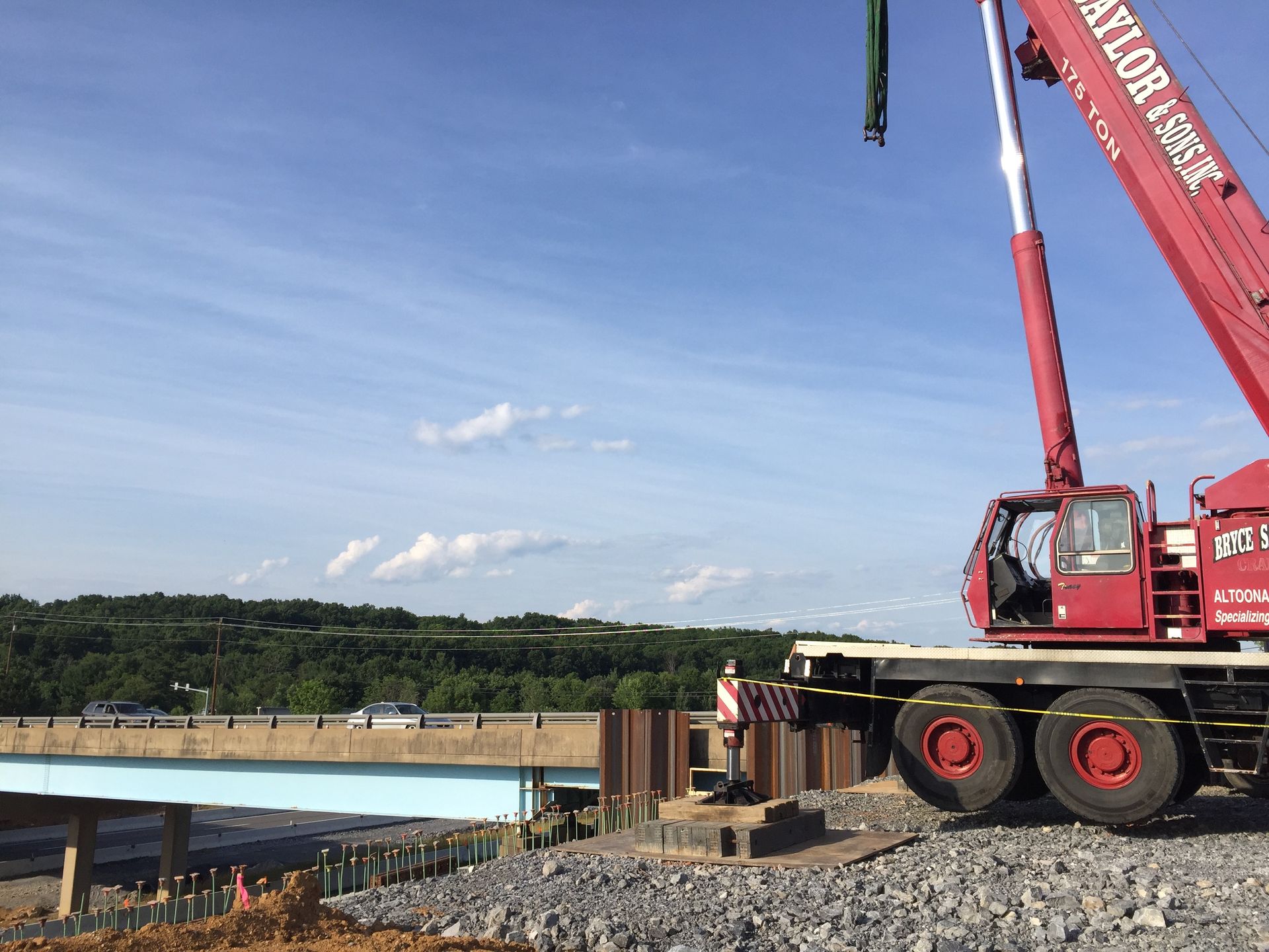 Red crane on a construction site beside a river under a clear blue sky