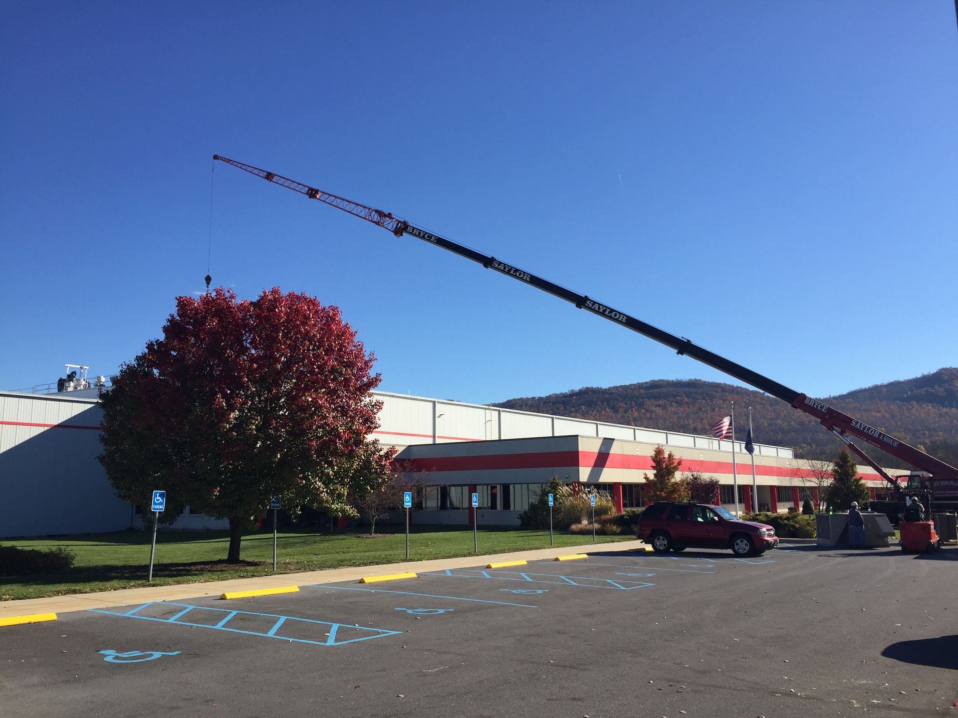 Parking lot with a crane lifting near a low building under a clear blue sky.